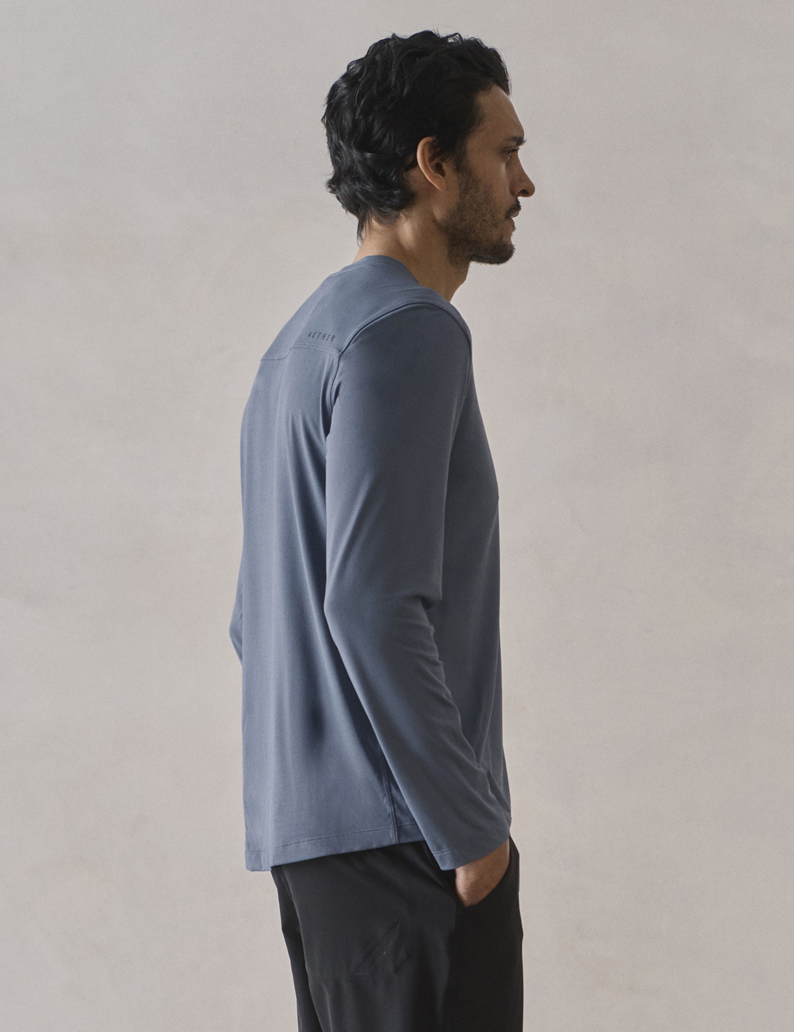 Rear 3/4 upper-body view of man wearing Adventure Performance Long-Sleeve Tee in Portal Blue from AETHER Apparel.