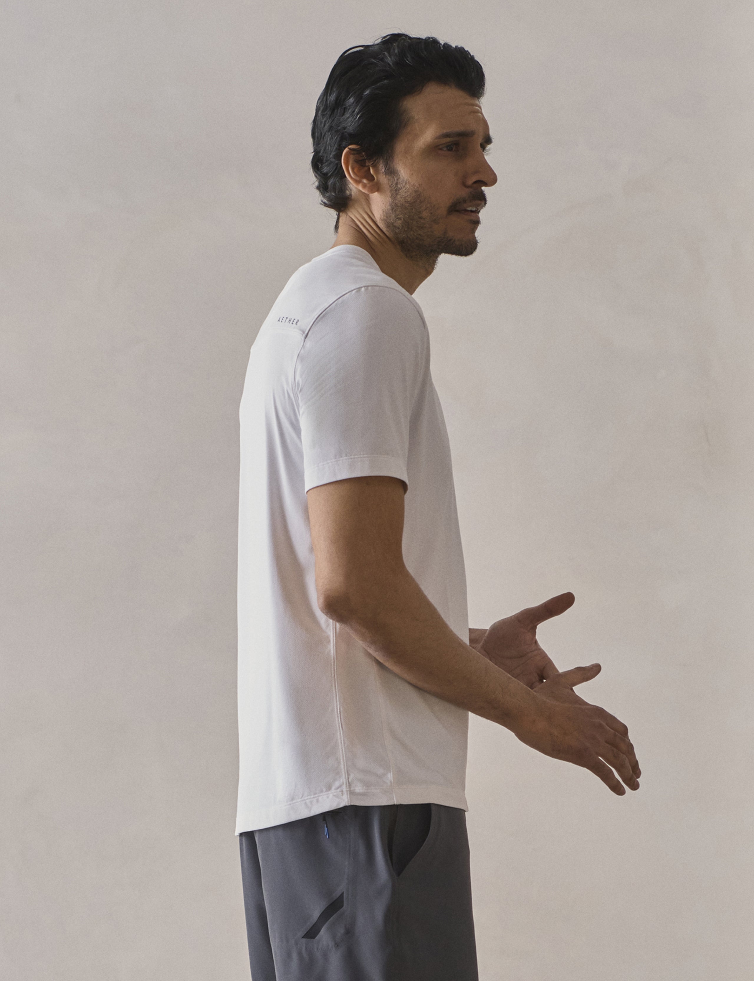 Right side profile upper-body view of man wearing Adventure Performance Short-Sleeve Tee in White from AETHER Apparel.