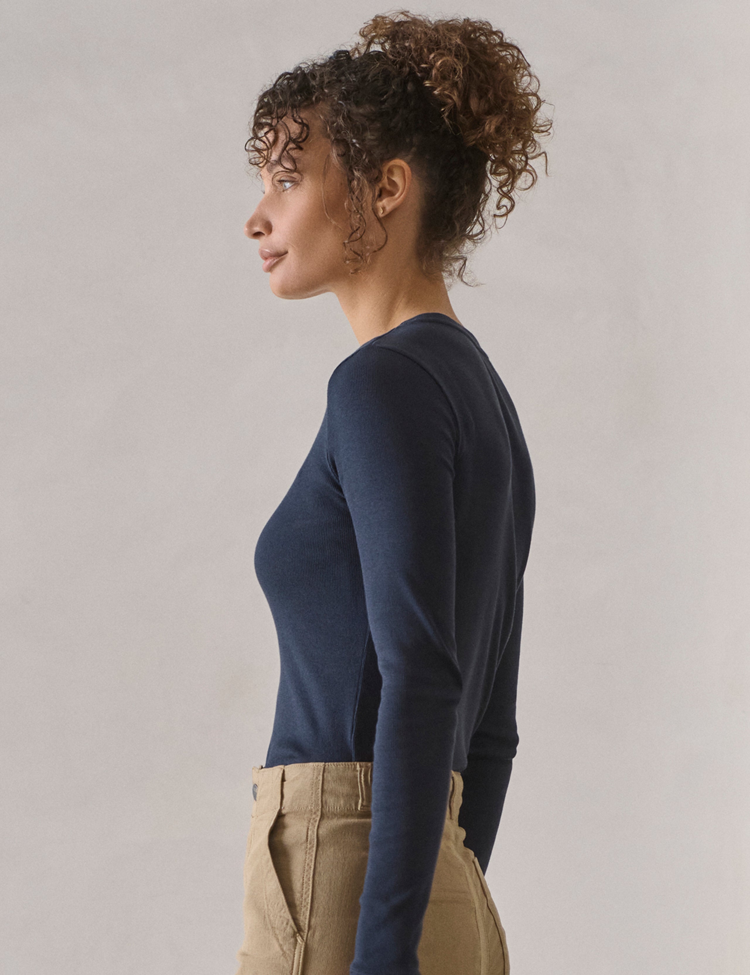 Side profile view of woman wearing Amara Long-Sleeve Crew in Total Eclipse dark blue from AETHER Apparel.