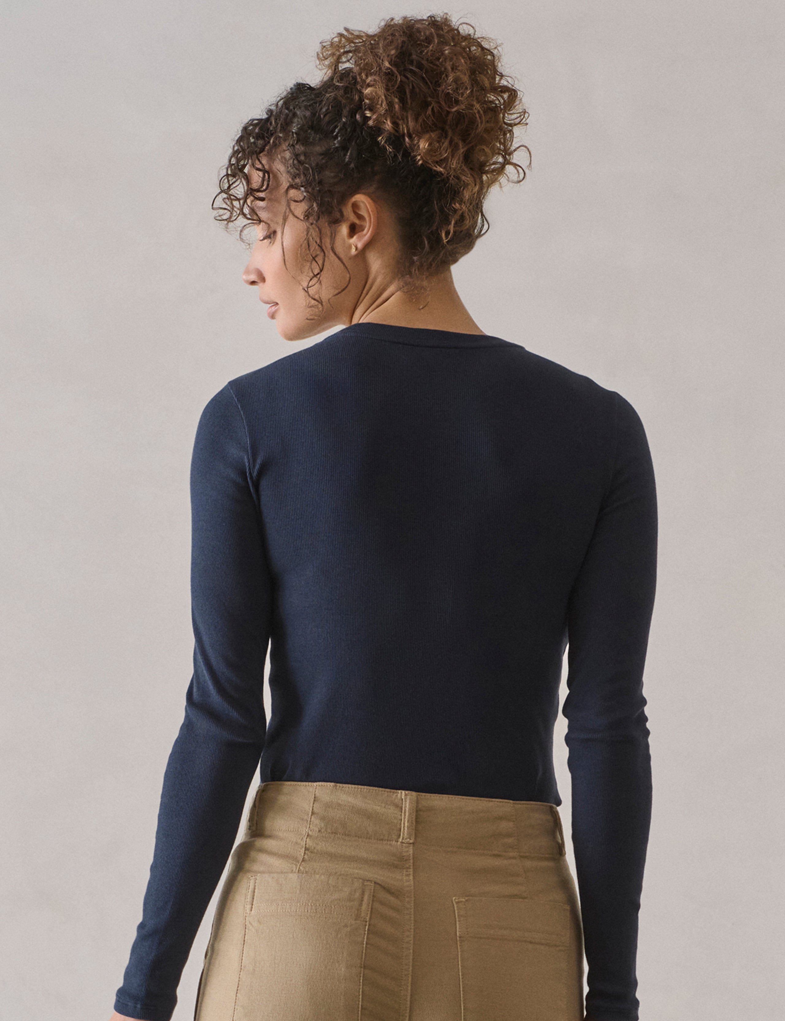 Rear view of woman wearing Amara Long-Sleeve Crew in Total Eclipse dark blue from AETHER Apparel.