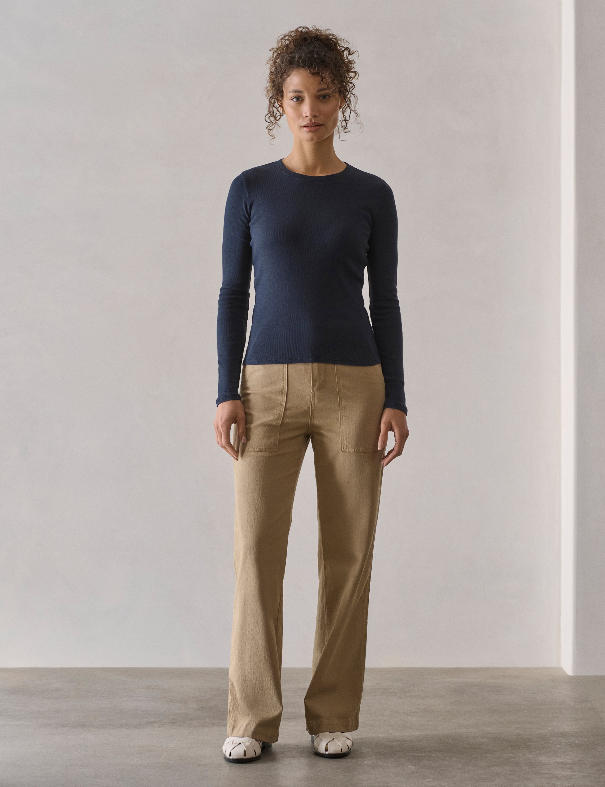 Front full-body view of woman wearing Amara Long-Sleeve Crew in Total Eclipse dark blue from AETHER Apparel.