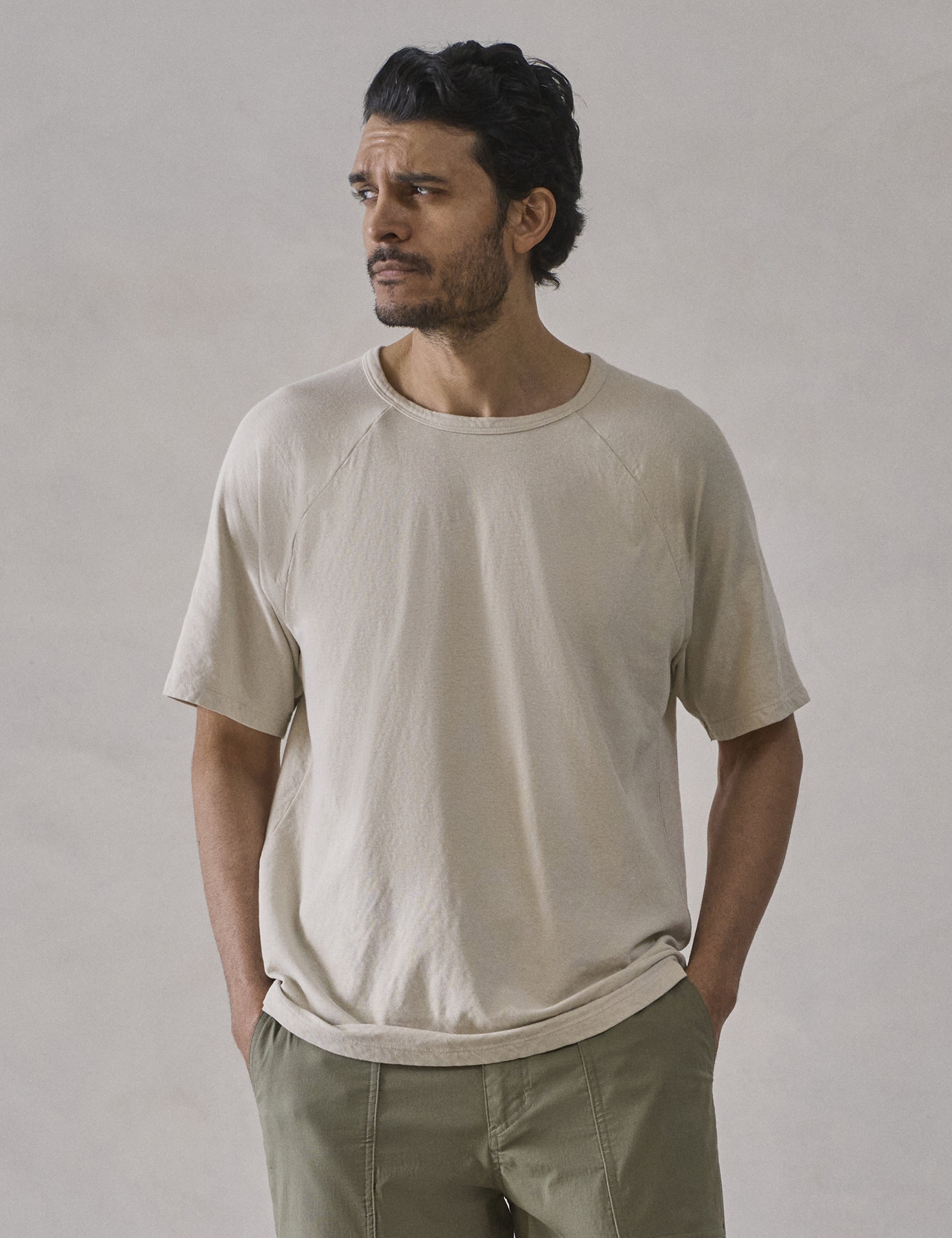 Front upper-body view of man wearing Buckhorn Cotton Raglan Tee 2.0 in Bone white from AETHER Apparel.