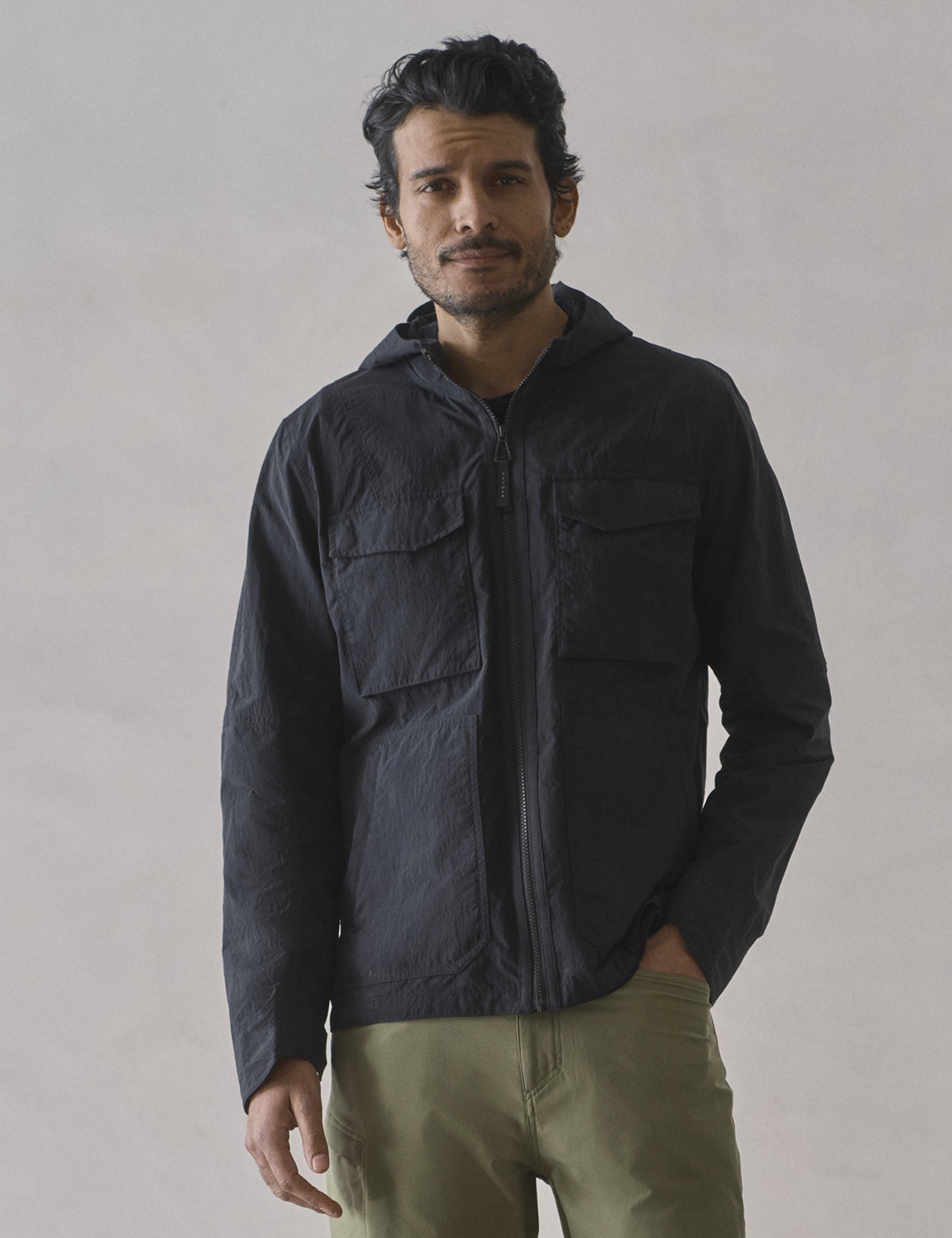 Front upper body view of man wearing Aires Lightweight Windbreaker in Onyx Black from AETHER Apparel.