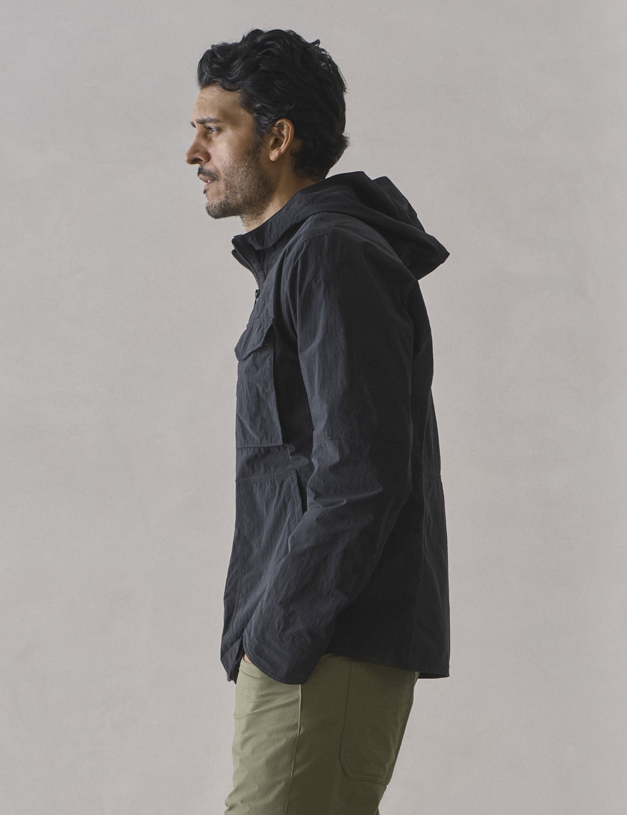 Side profile view of man wearing Aires Lightweight Windbreaker in Onyx Black from AETHER Apparel.