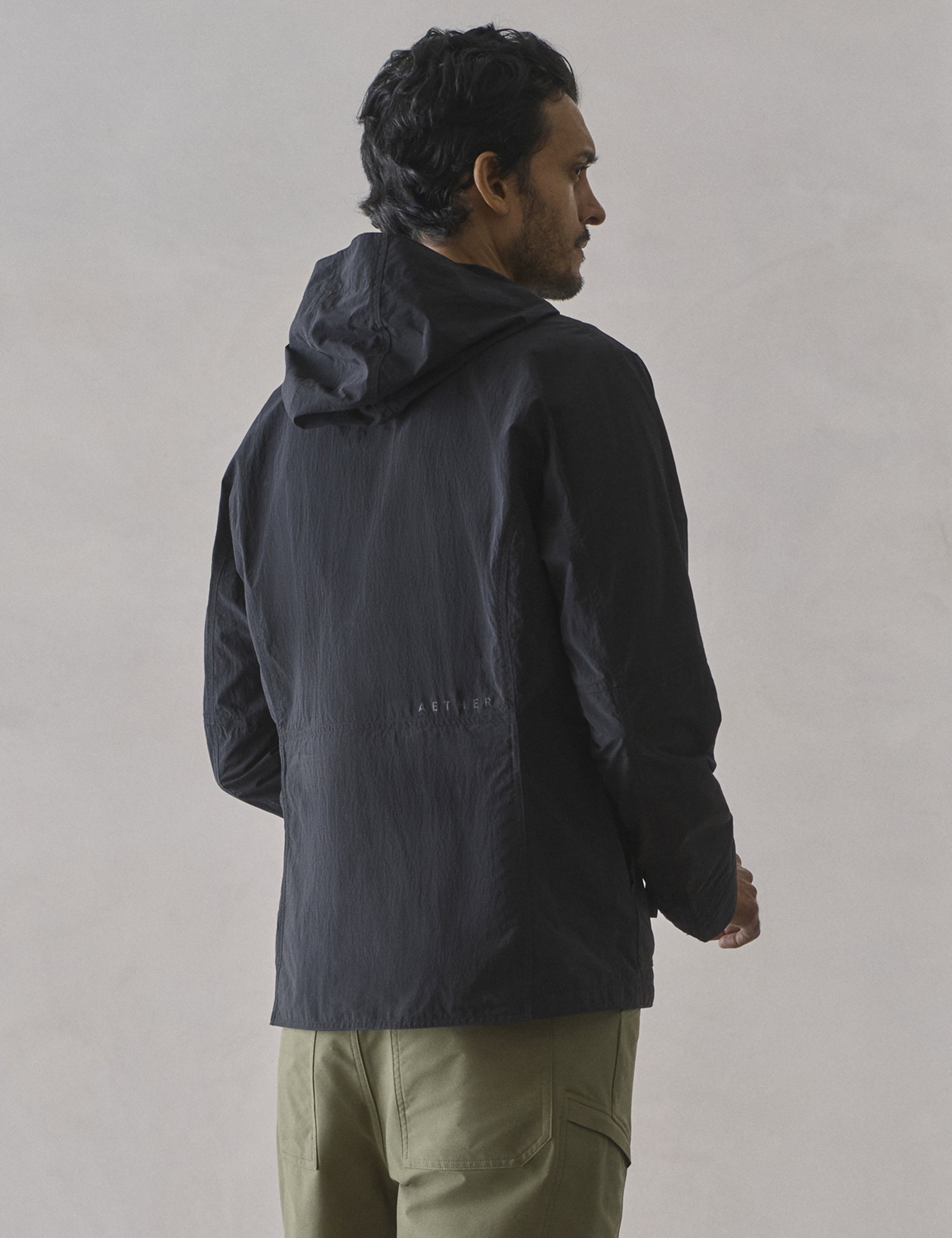 Rear 3/4 body view of man wearing Aires Lightweight Windbreaker in Onyx Black from AETHER Apparel.