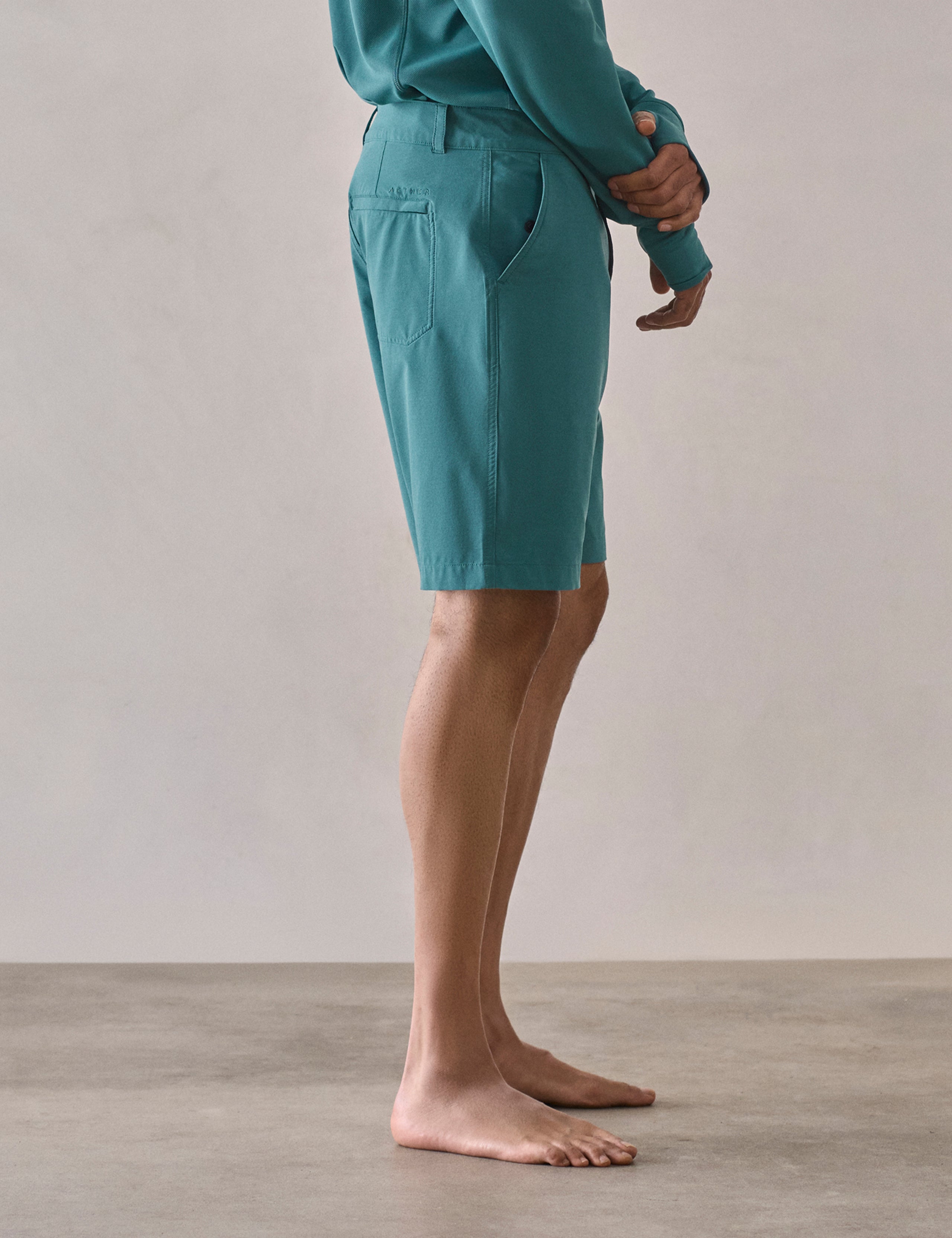 Side profile lower-body view of man wearing Catalina Submersible Short in Aqua Blue from AETHER Apparel.
