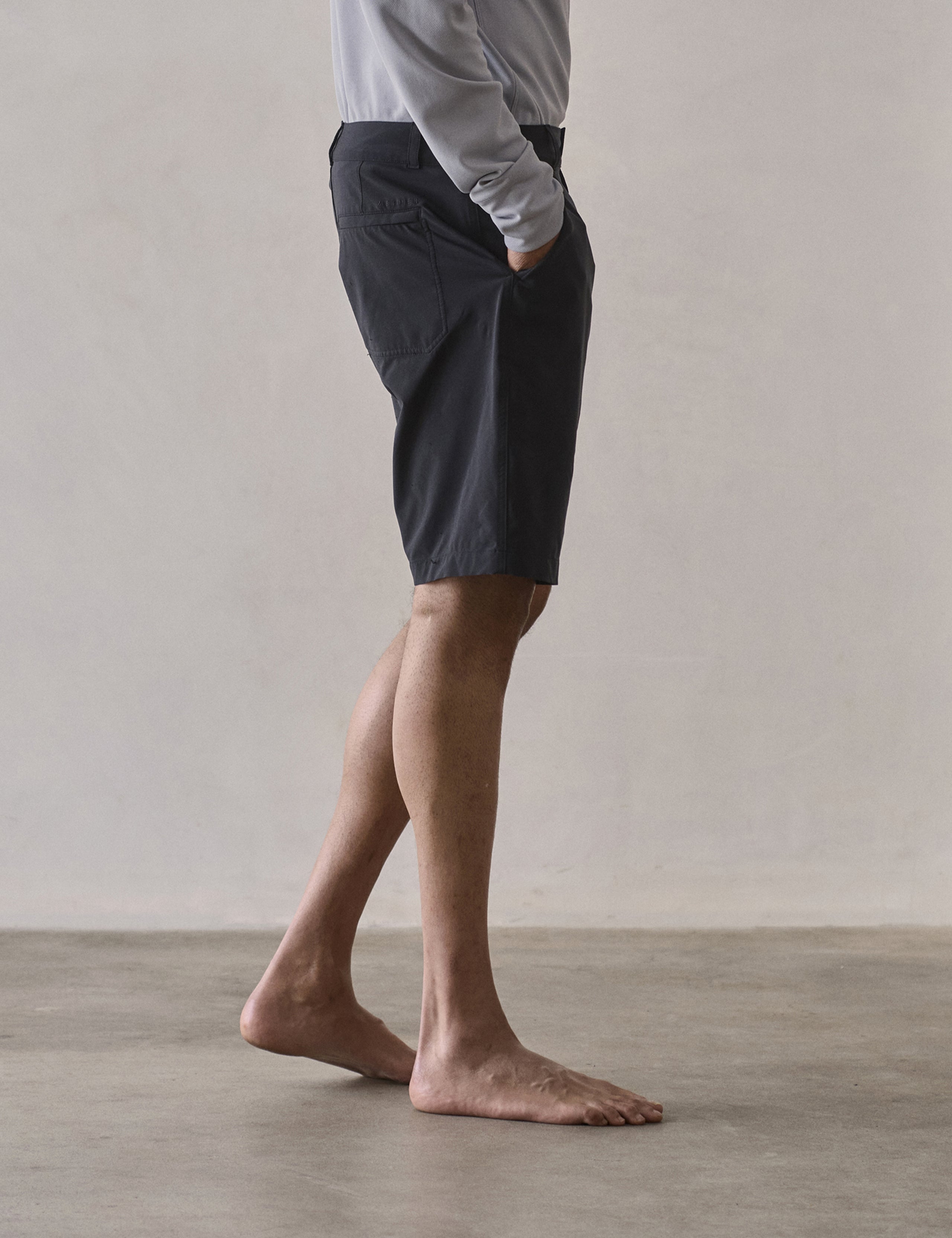 Side profile lower-body view of man wearing Catalina Submersible Short in Onyx Black from AETHER Apparel.