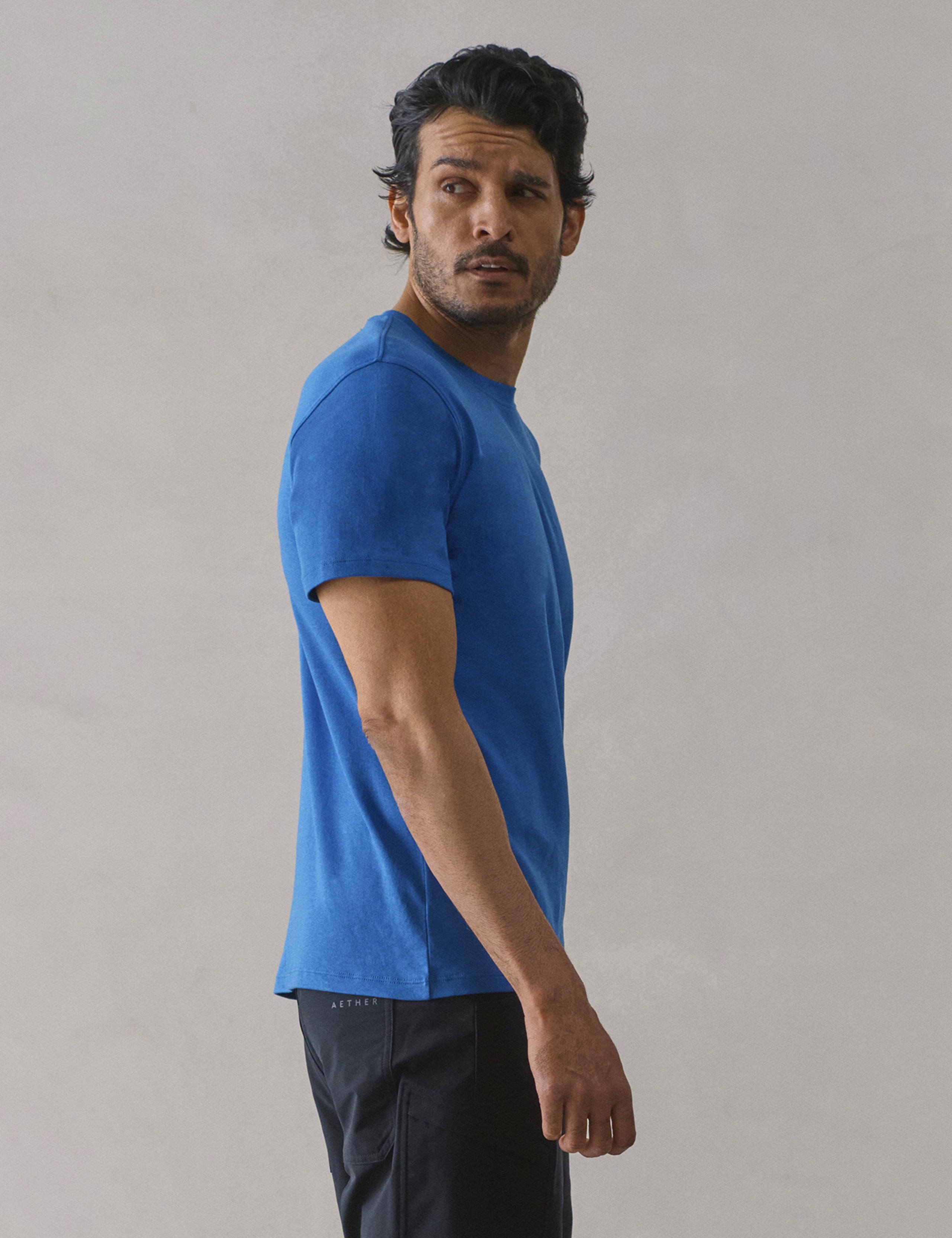 Side profile view of man wearing Emery Pima Crew Tee in Summit Blue from AETHER Apparel.