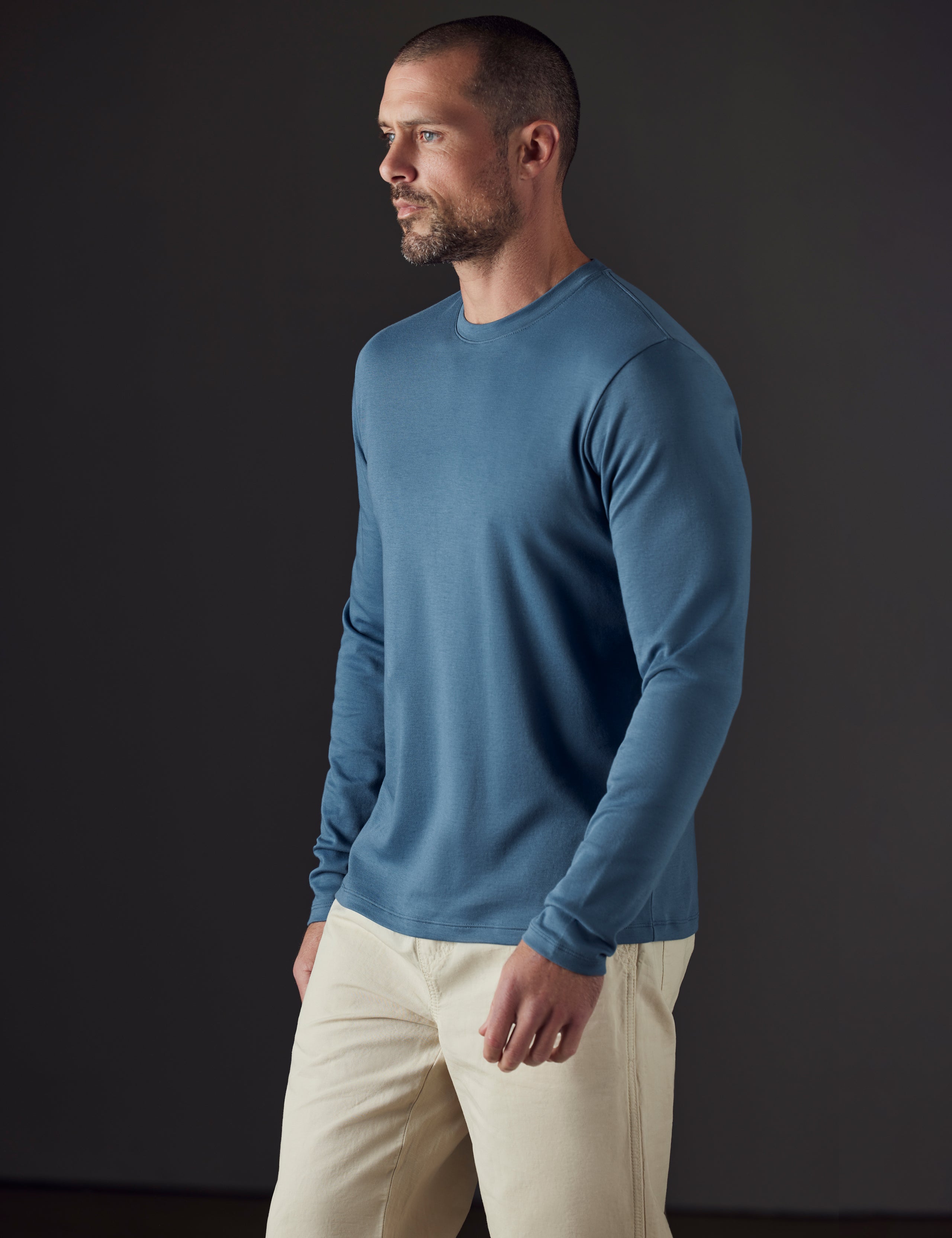Front 3/4 body view of man wearing Emery Pima Long-Sleeve Tee in Coastal Blue from AETHER Apparel.