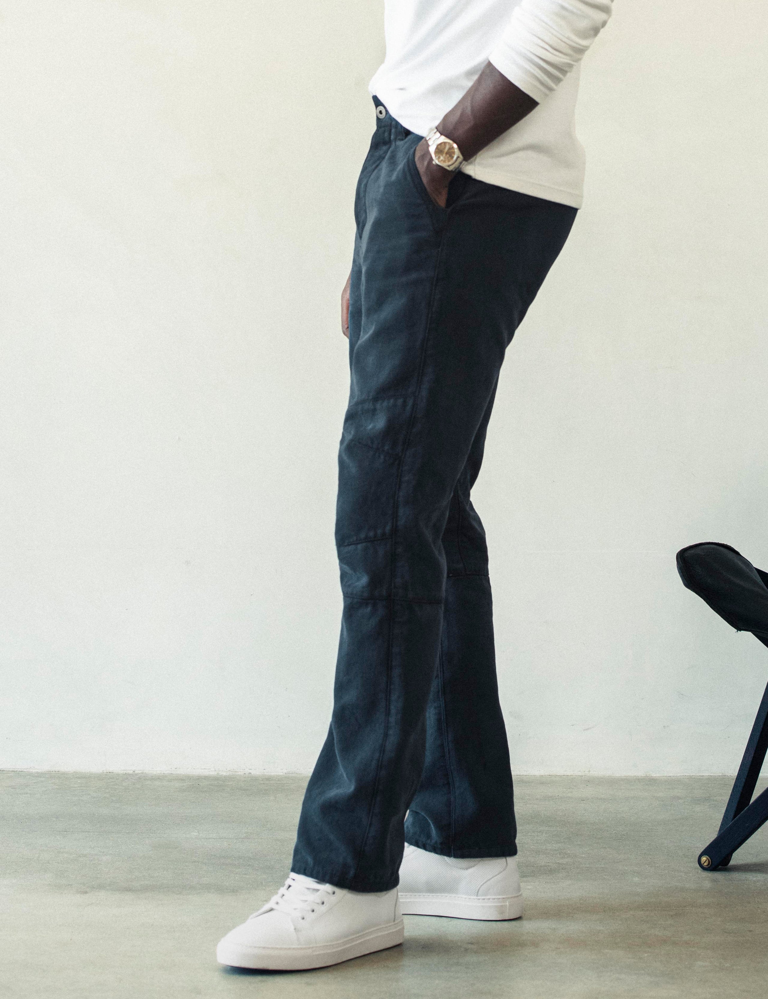 Side profile lower body view of man wearing Gabriel Articulated Chino Stretch pant in Total Eclipse dark blue from AETHER Apparel.