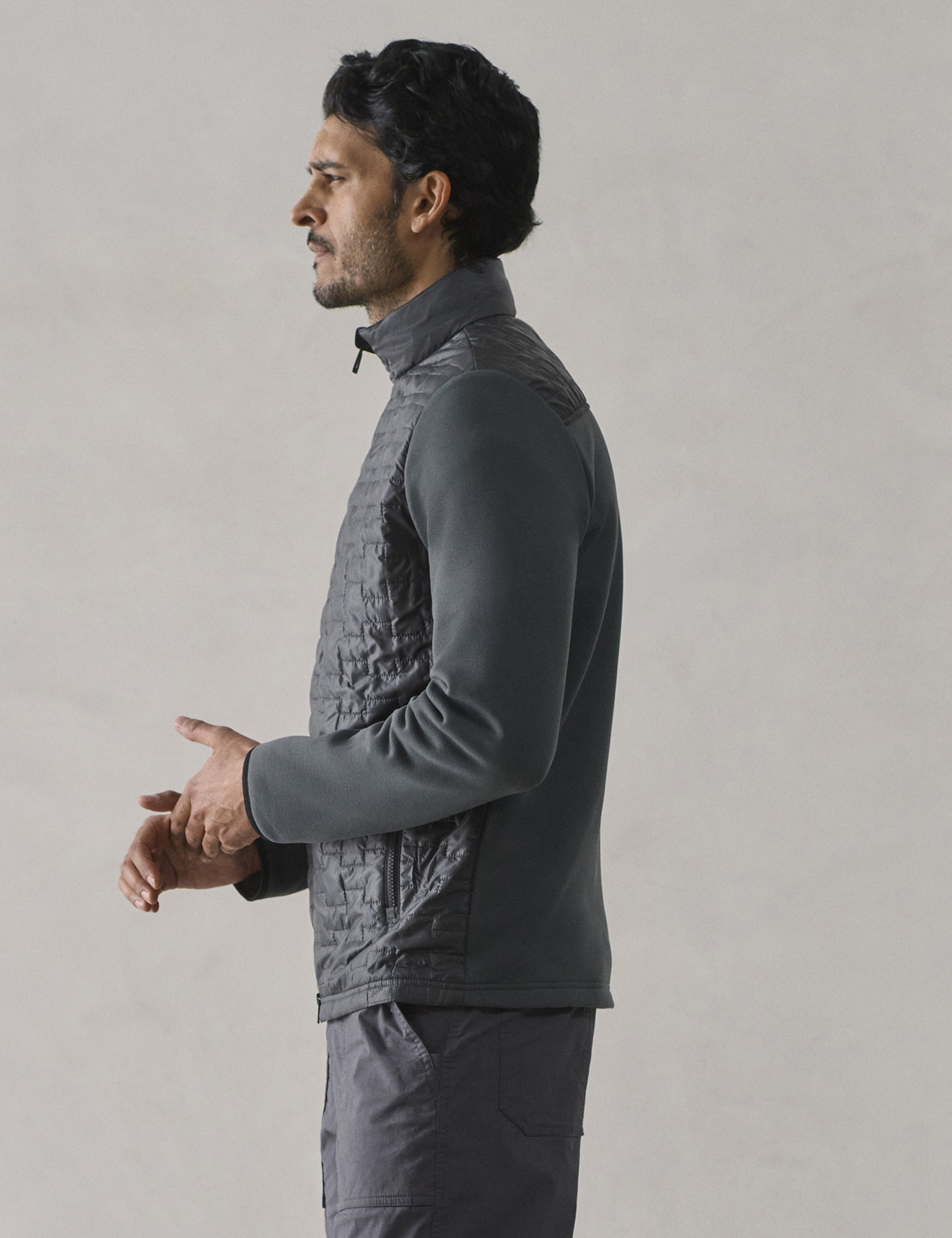 Side profile view of man wearing Hybrid Tech Full-Zip in Graphite from AETHER Apparel.