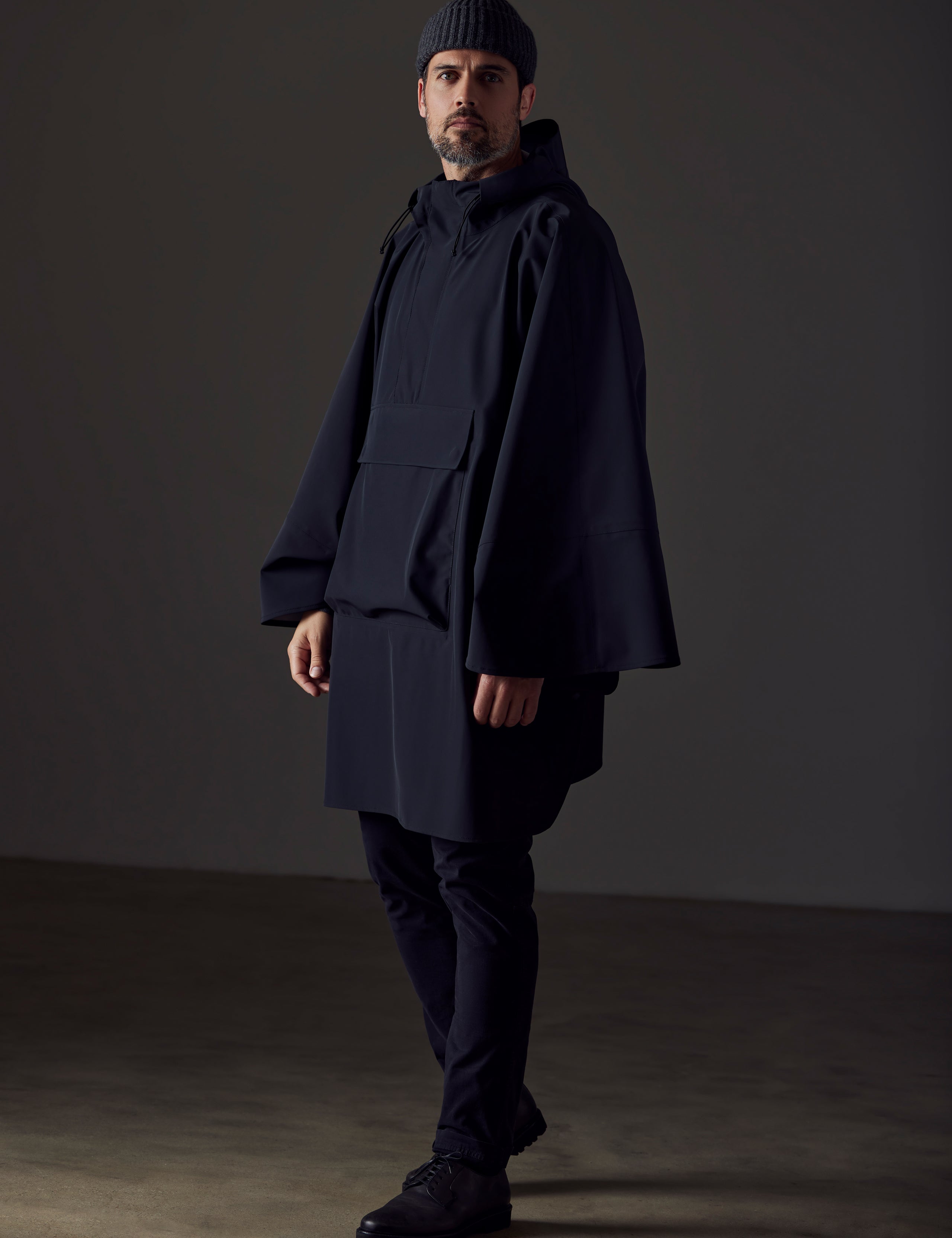 Full-body view of man wearing black Line Poncho from AETHER Apparel.