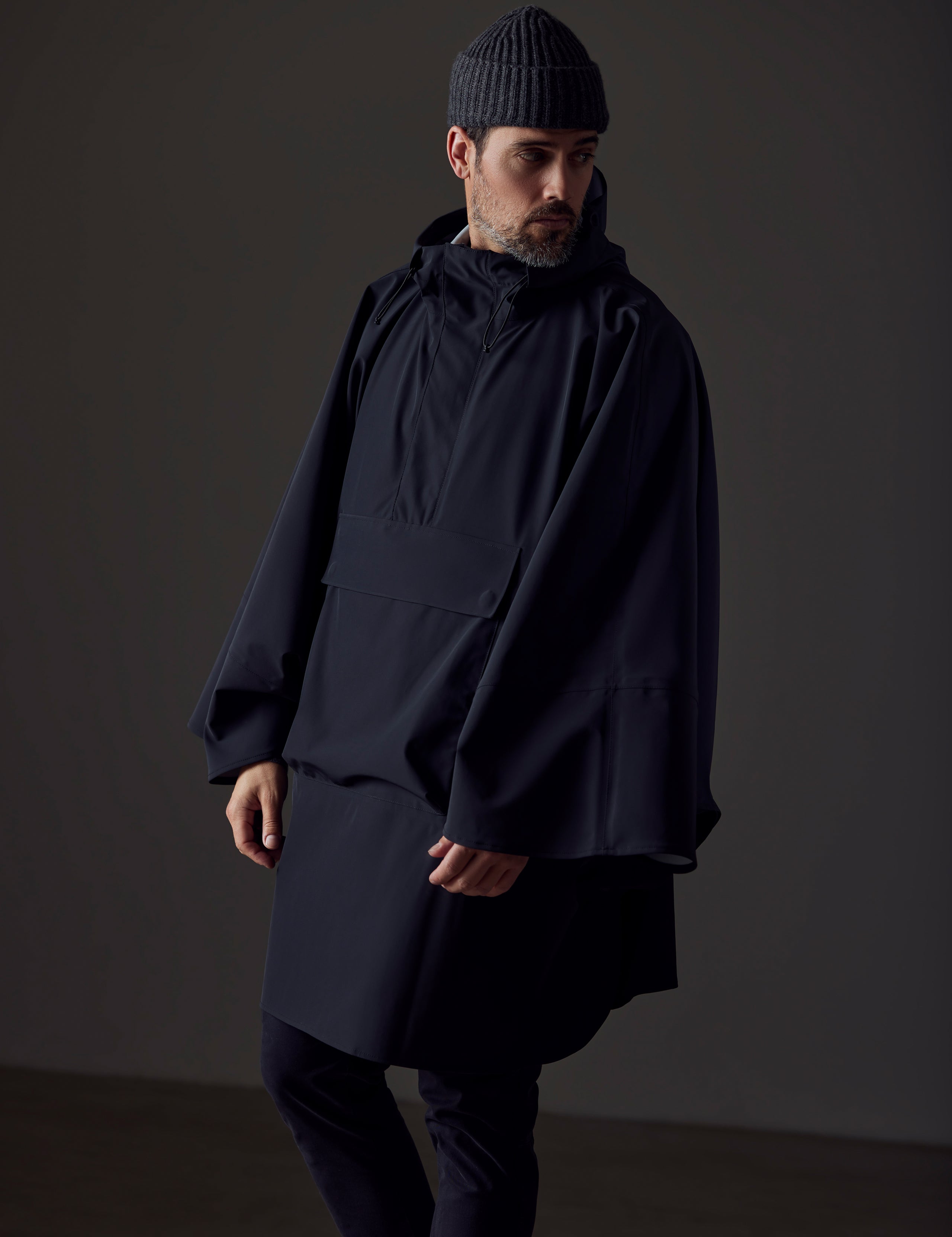 Front right-angled view of man wearing black Line Poncho from AETHER Apparel.