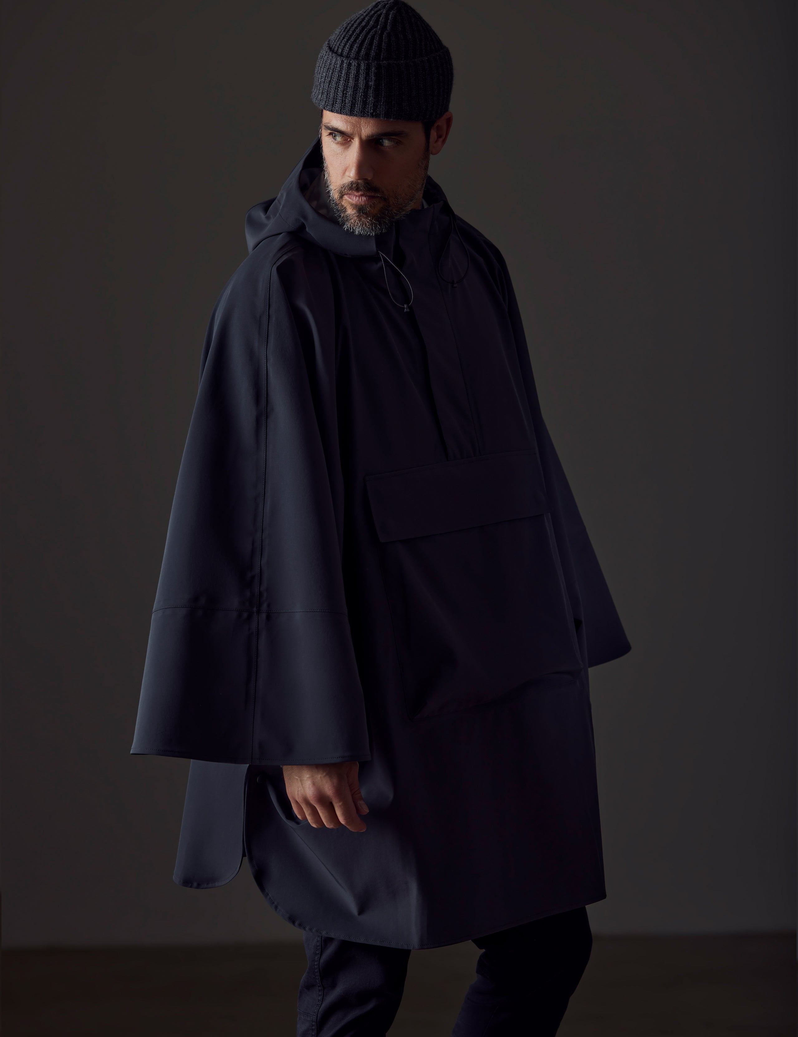 Front left-angled view of man wearing black Line Poncho from AETHER Apparel.