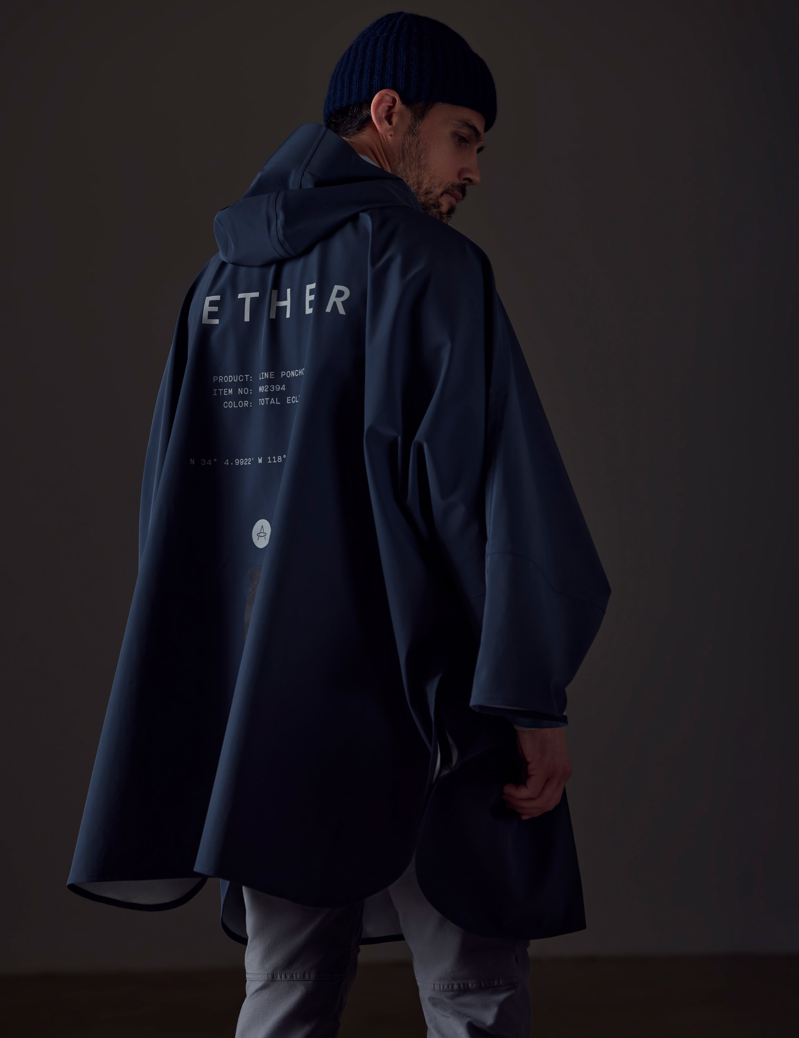 Back view of man wearing blue Line Poncho from AETHER Apparel.