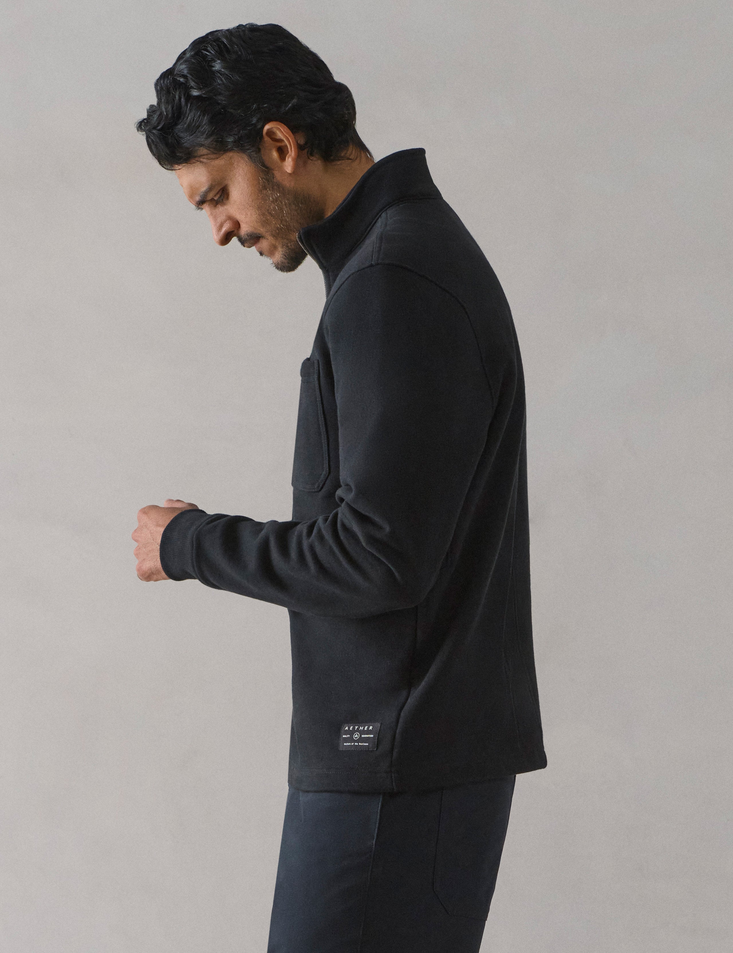 Side profile view of man wearing Monte Half-Zip Sweatshirt in Onyx Black from AETHER Apparel.
