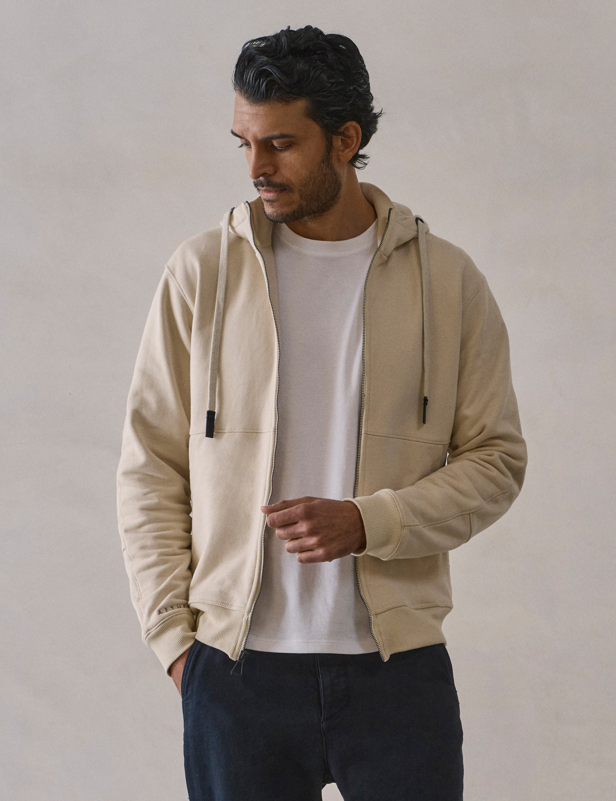Front upper body view of man wearing Monte Full-Zip Hoodie in Bone white from AETHER Apparel.