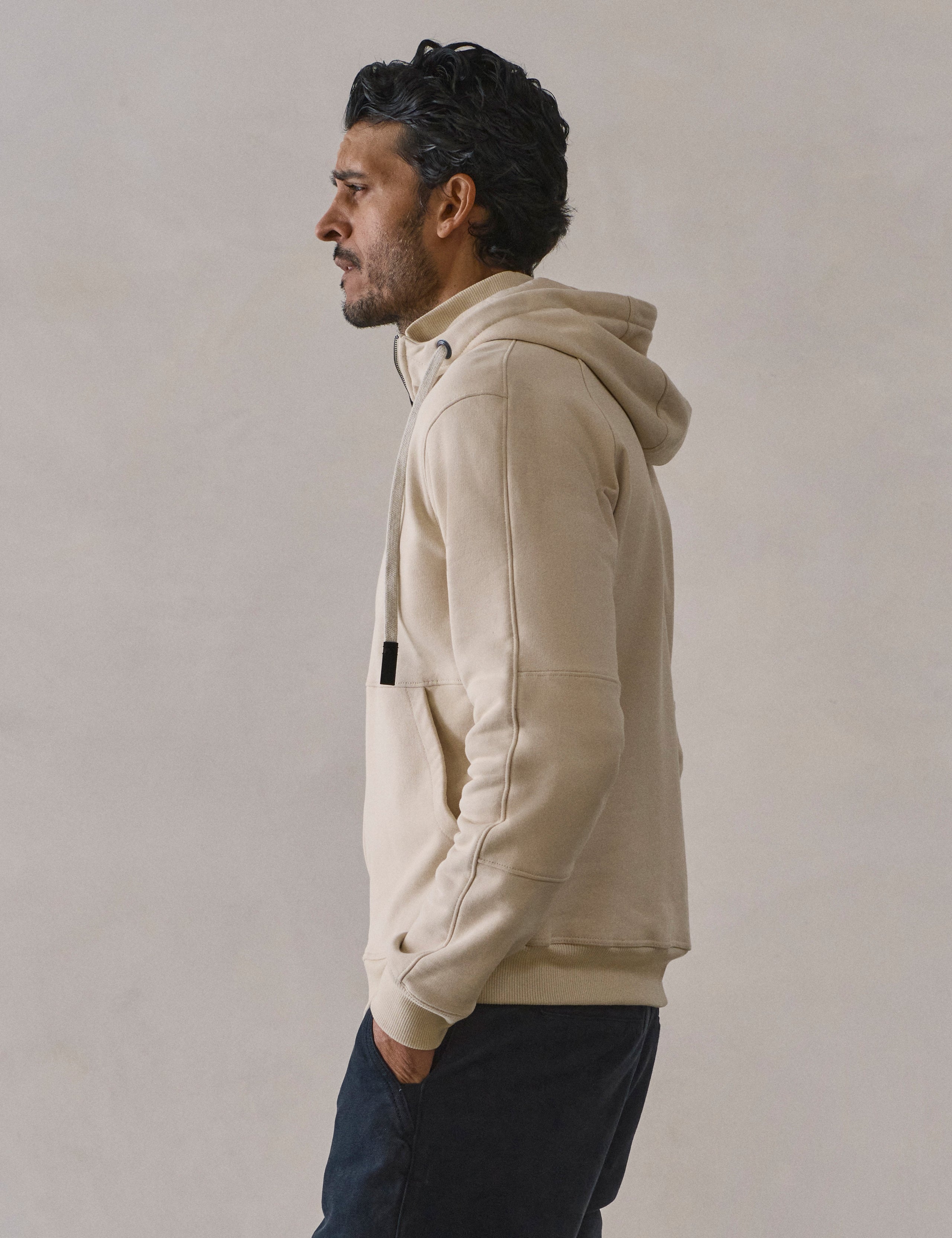 Side profile view of man wearing Monte Full-Zip Hoodie in Bone white from AETHER Apparel.