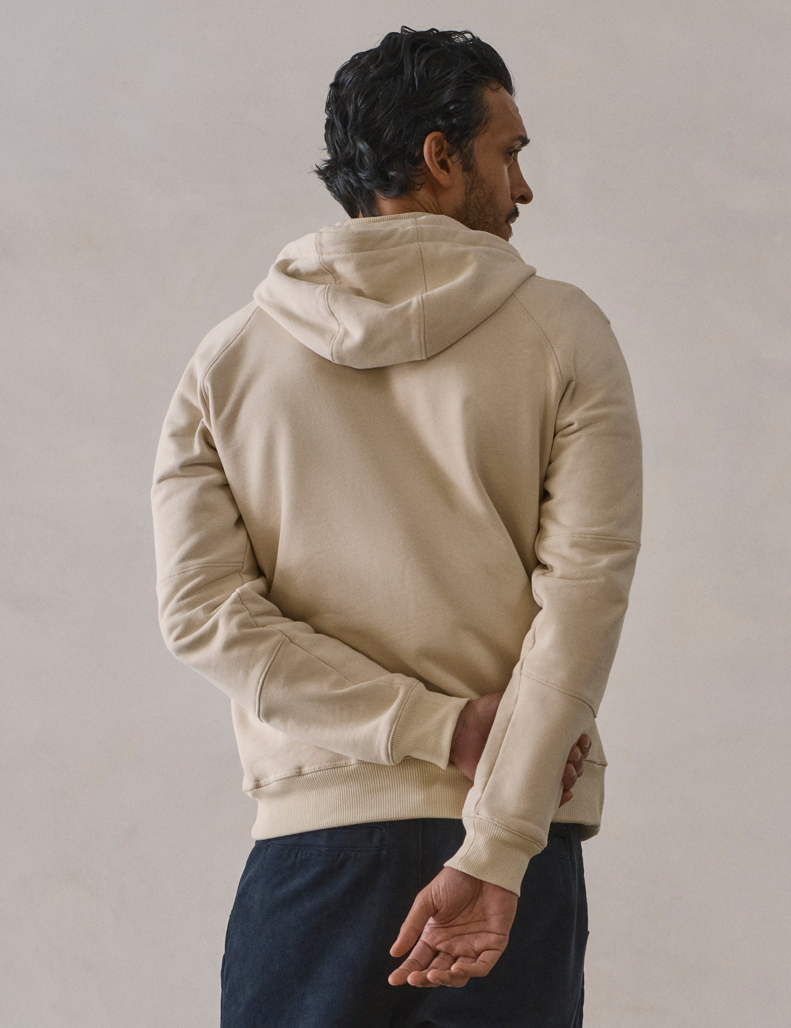 Rear view of man wearing Monte Full-Zip Hoodie in Bone white from AETHER Apparel.