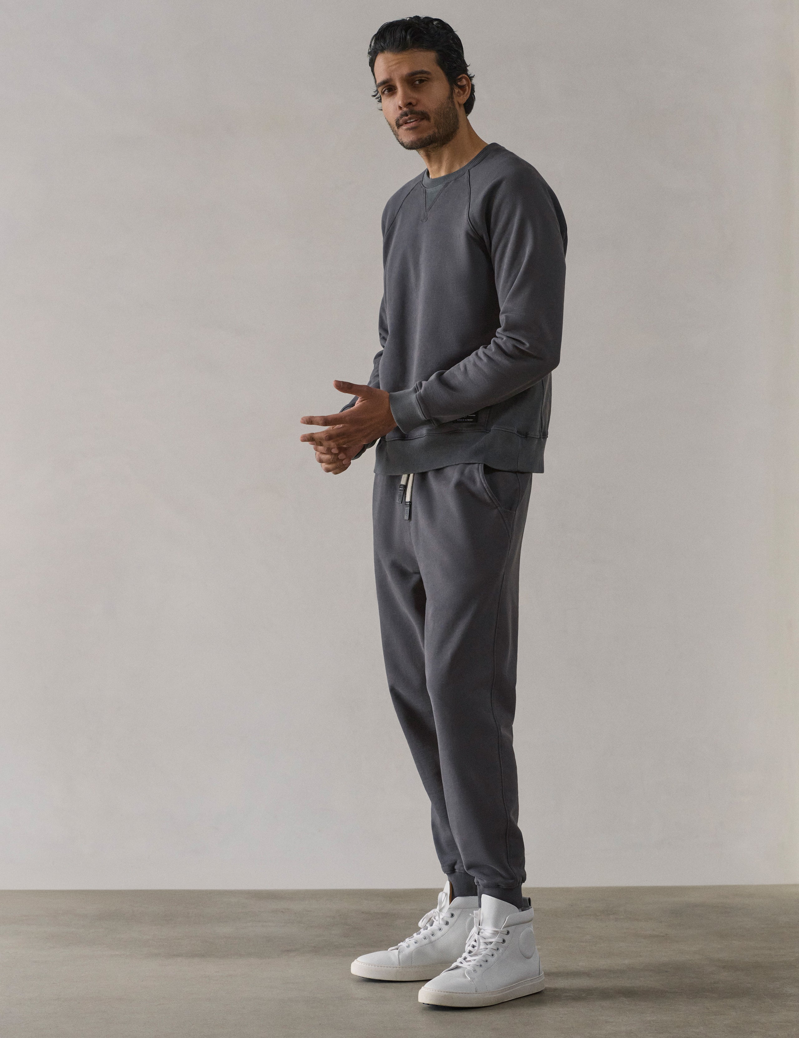 Front 3/4 full-body view of man wearing Osa Raglan Sweatshirt in Graphite grey from AETHER Apparel.