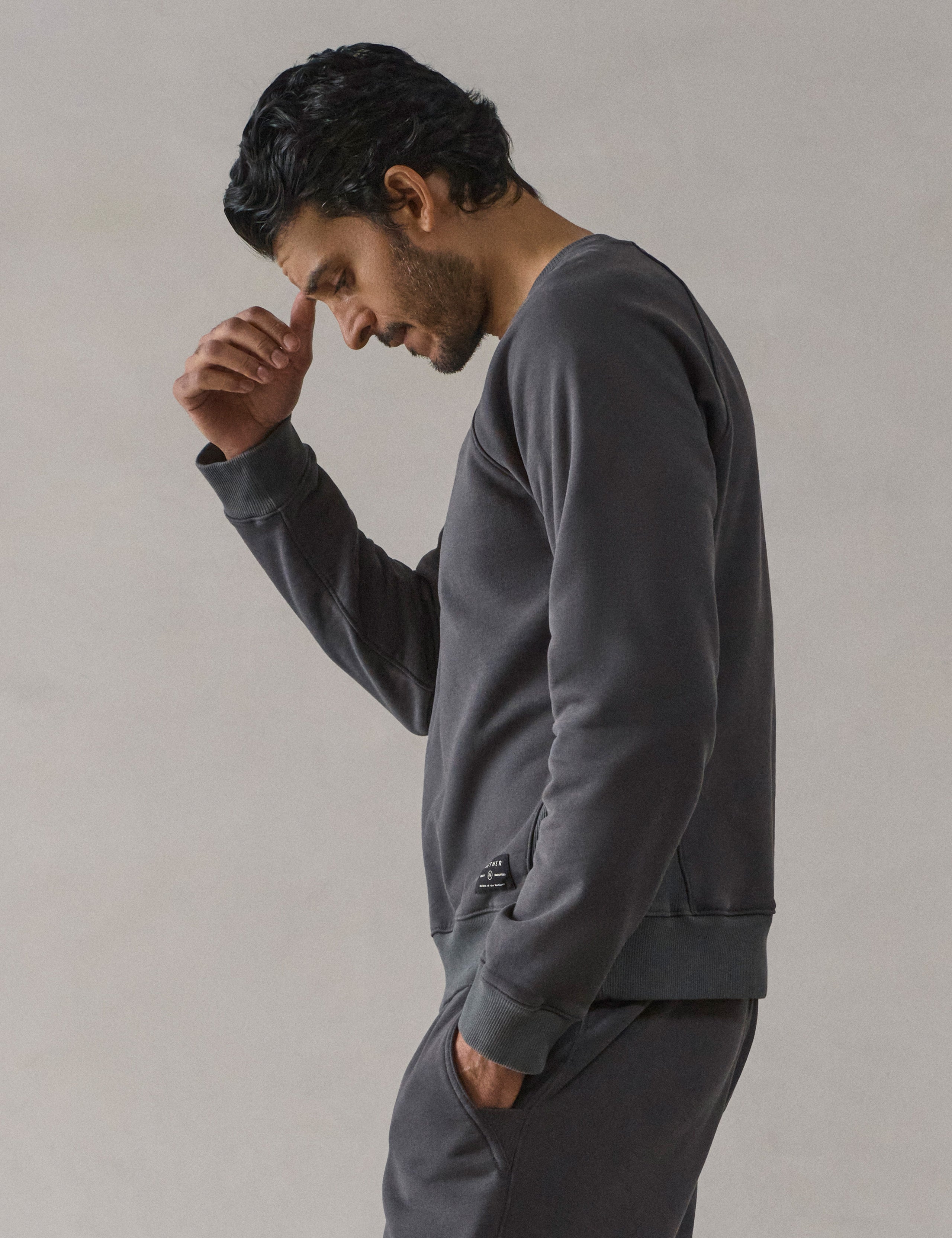 Left side profile upper-body view of man wearing Osa Raglan Sweatshirt in Graphite grey from AETHER Apparel.
