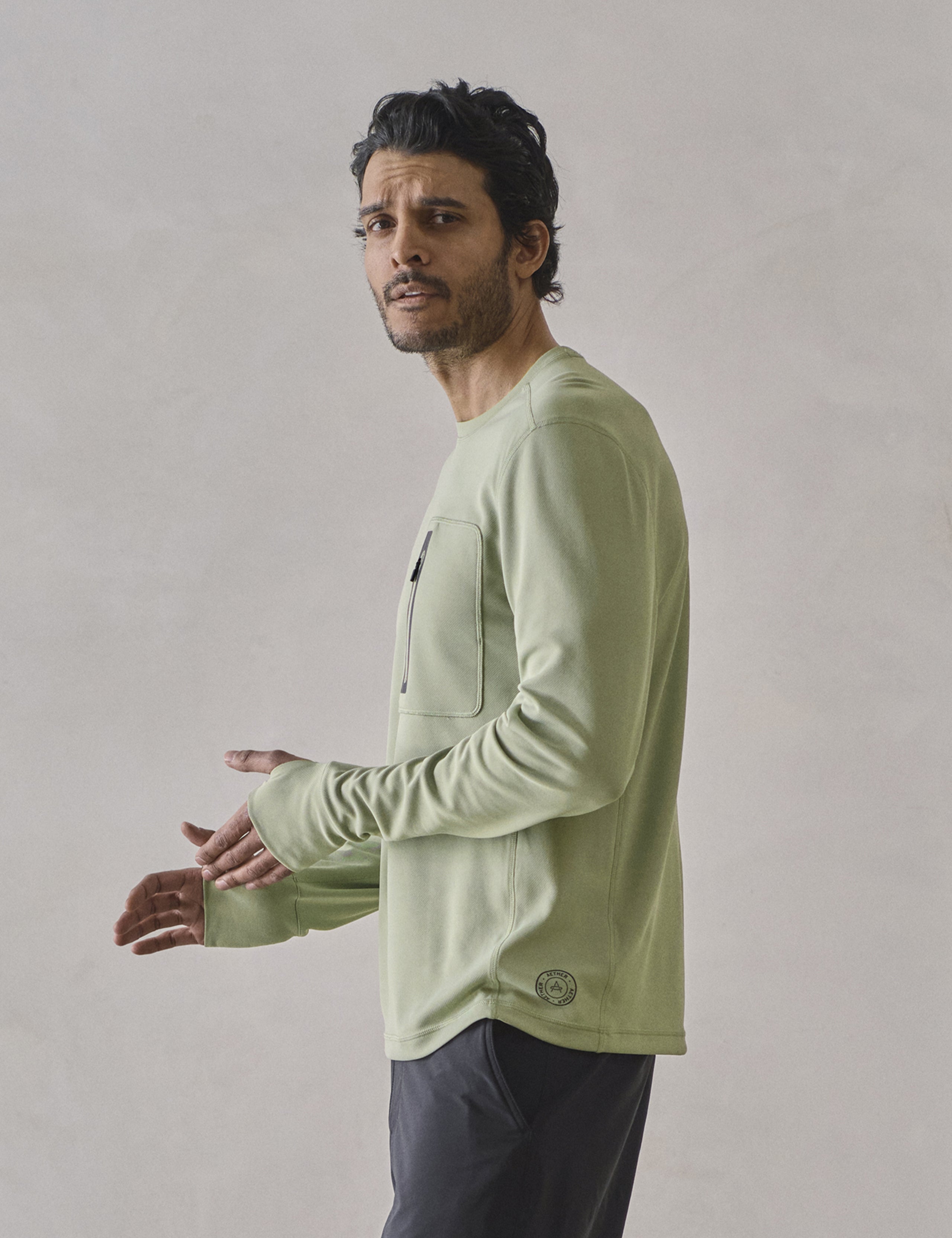 Side profile upper-body view of man wearing Pacific Crewneck Sun Shirt in Sage Green from AETHER Apparel.
