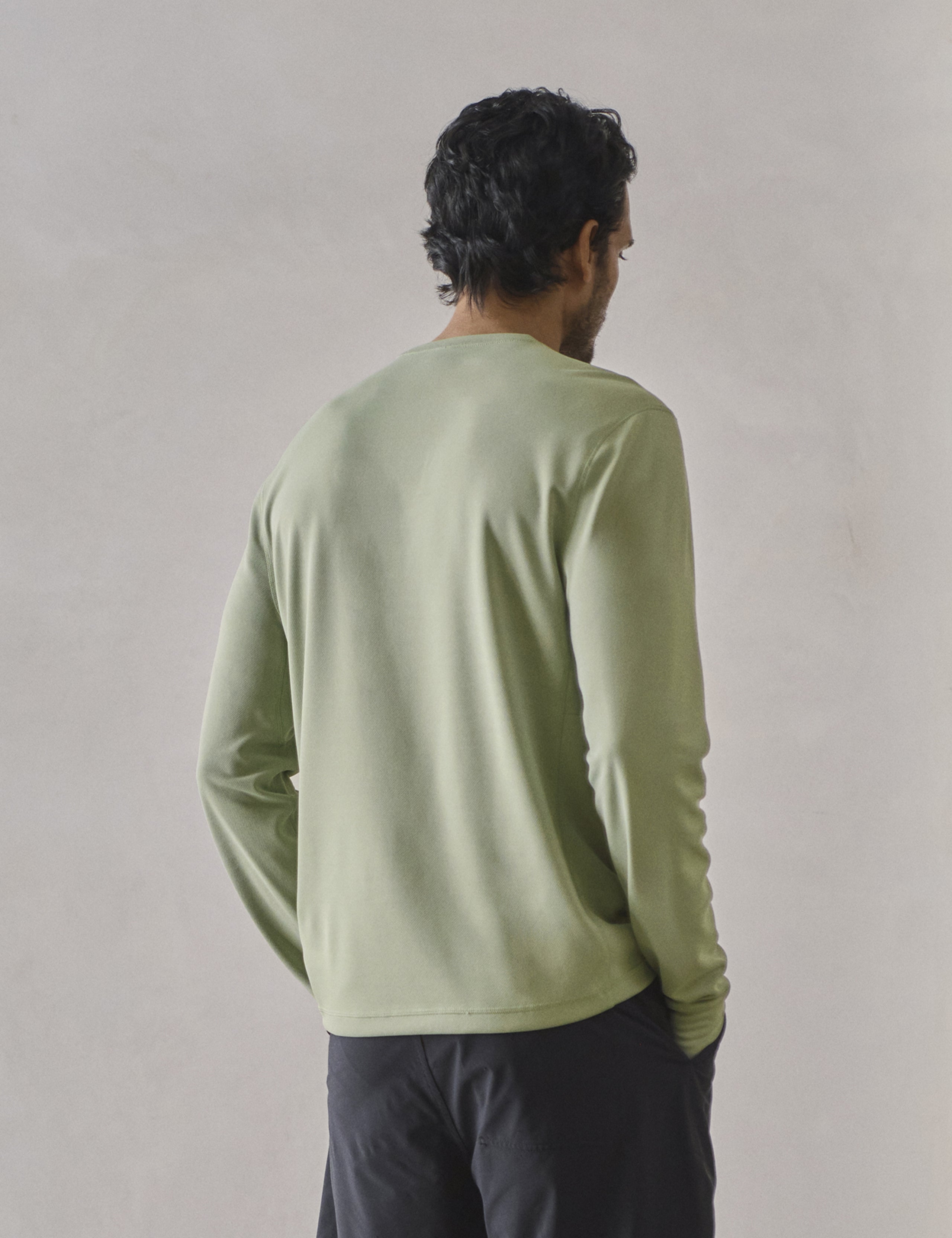 Rear 3/4 upper-body view of man wearing Pacific Crewneck Sun Shirt in Sage Green from AETHER Apparel.