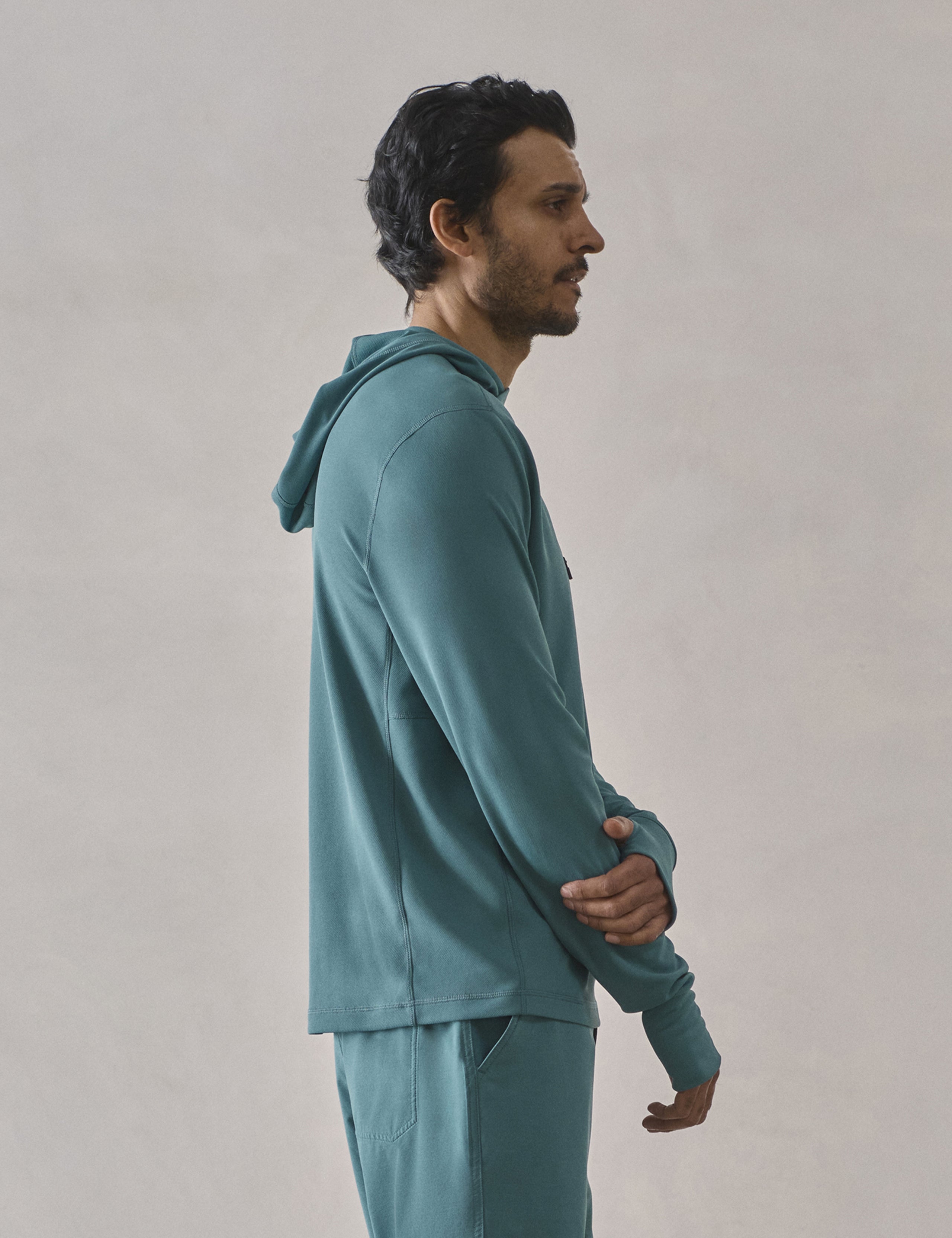 Side profile upper-body view of man wearing Pacific Hooded Sun Shirt in Aqua Blue from AETHER Apparel.