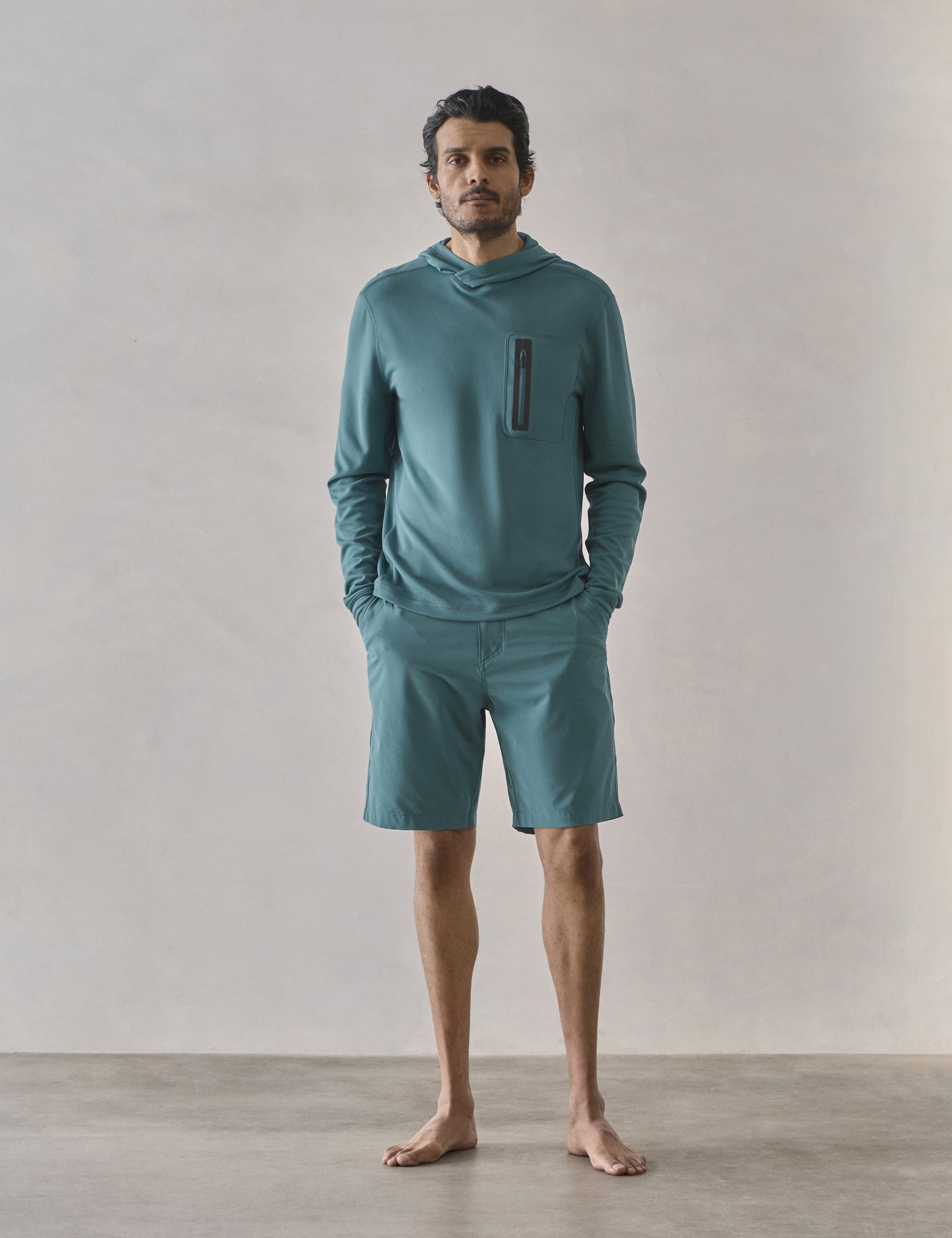Front full-body view of man wearing Pacific Hooded Sun Shirt in Aqua Blue from AETHER Apparel.