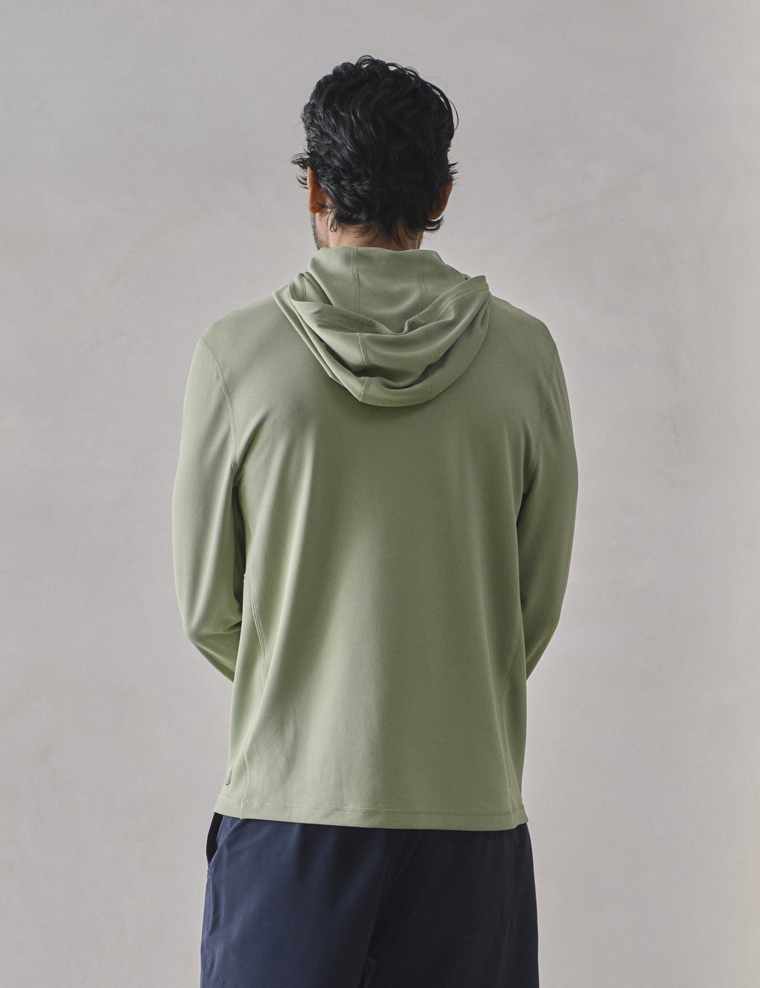 Rear upper-body view of man wearing Pacific Hooded Sun Shirt in Aqua Blue from AETHER Apparel.