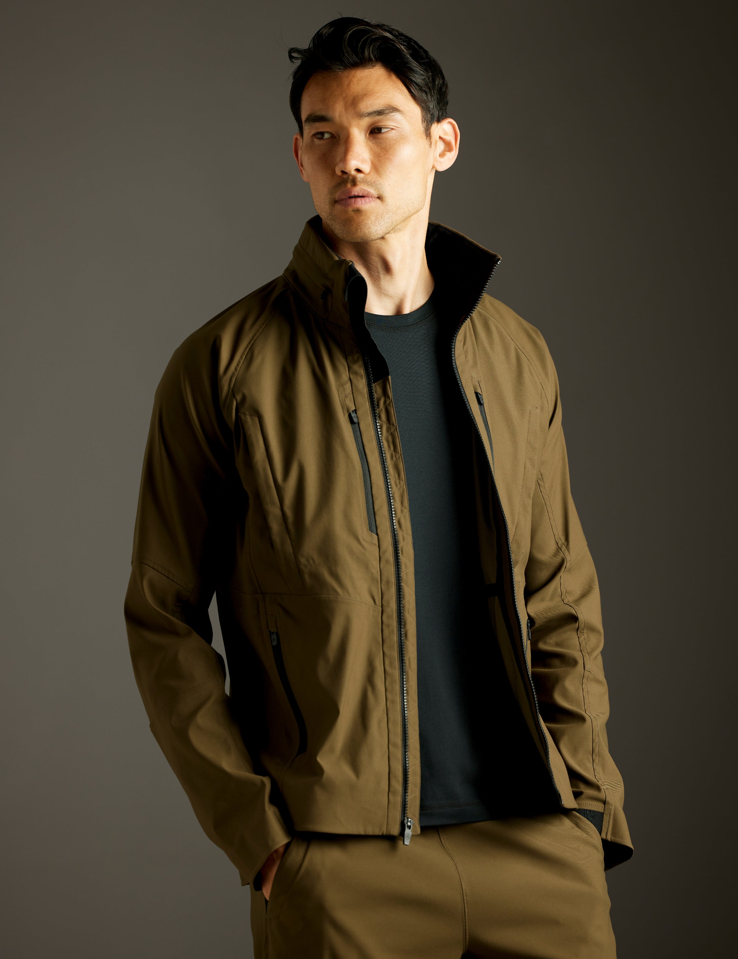 Front 3/4 body view of man wearing unzipped Perth Vented Jacket in Cadet Green from AETHER Apparel.