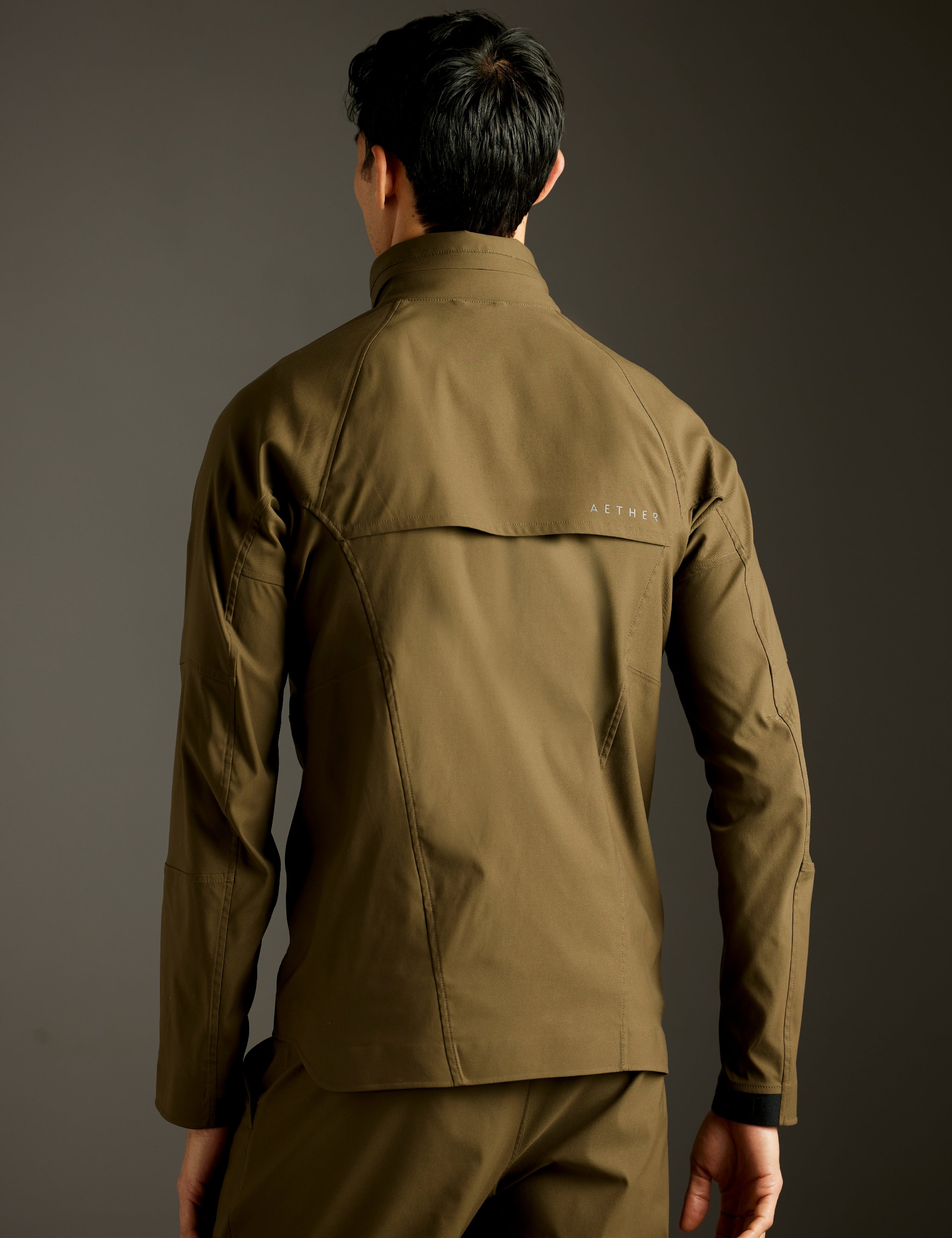 Rear 3/4 body view of man wearing Perth Vented Jacket in Cadet Green from AETHER Apparel.