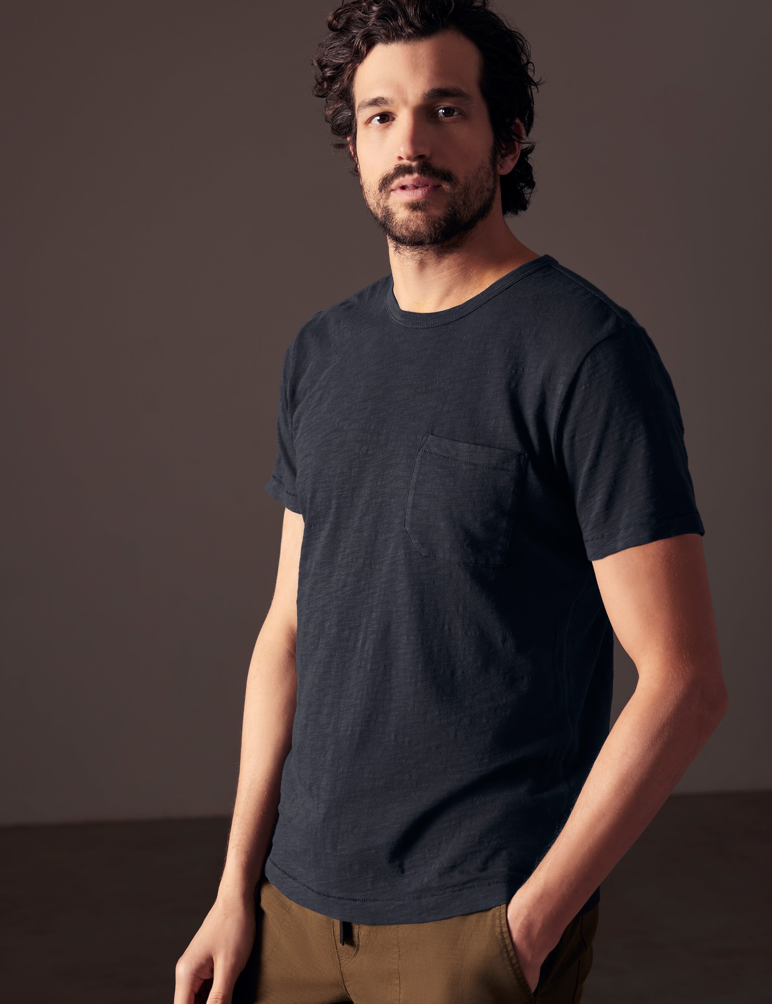 Front angled body view of man wearing Slub Pocket Tee in Total Eclipse dark blue from AETHER Apparel.