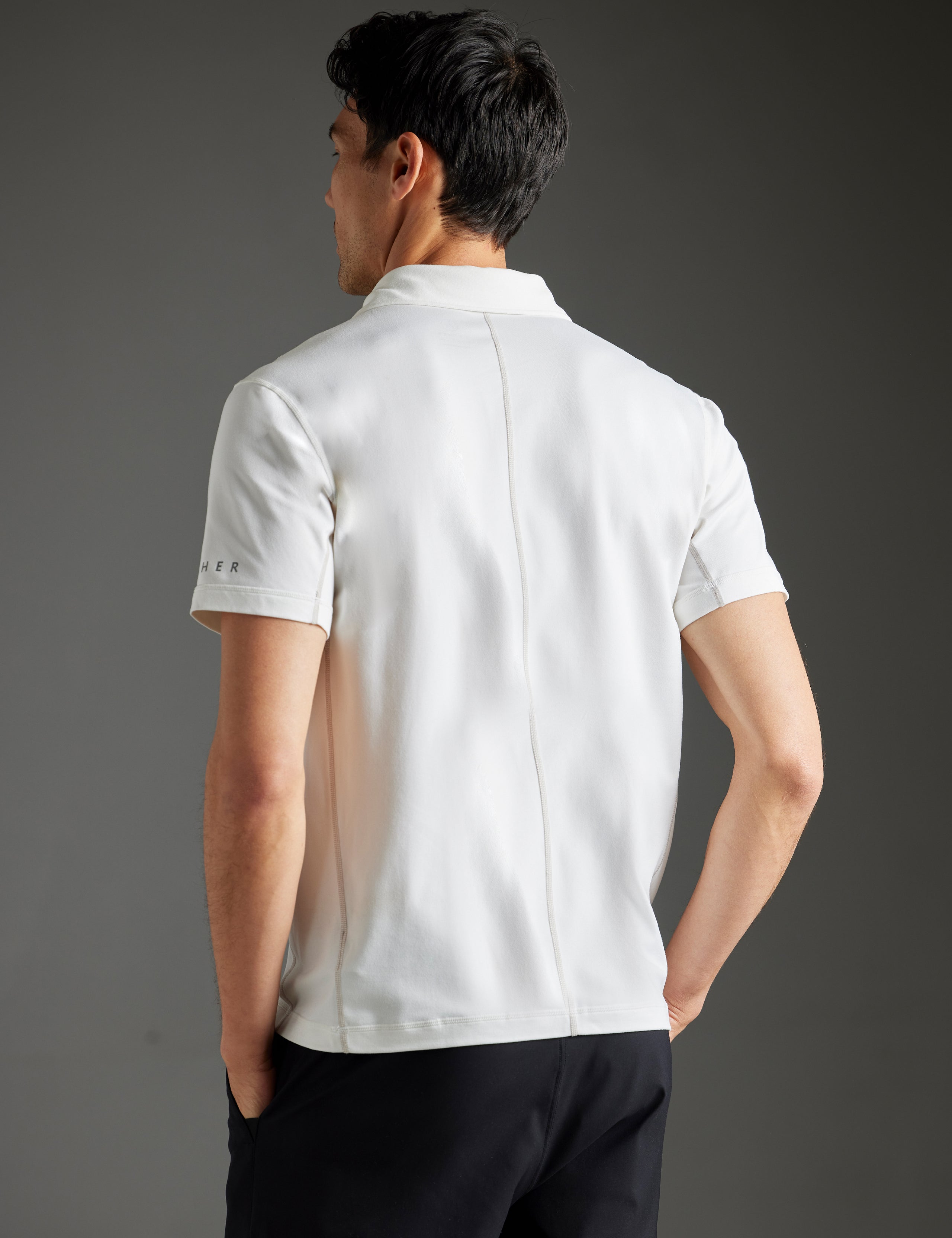 Rear 3/4 body view of man wearing Trek Articulated Polo in Natural White from AETHER Apparel.