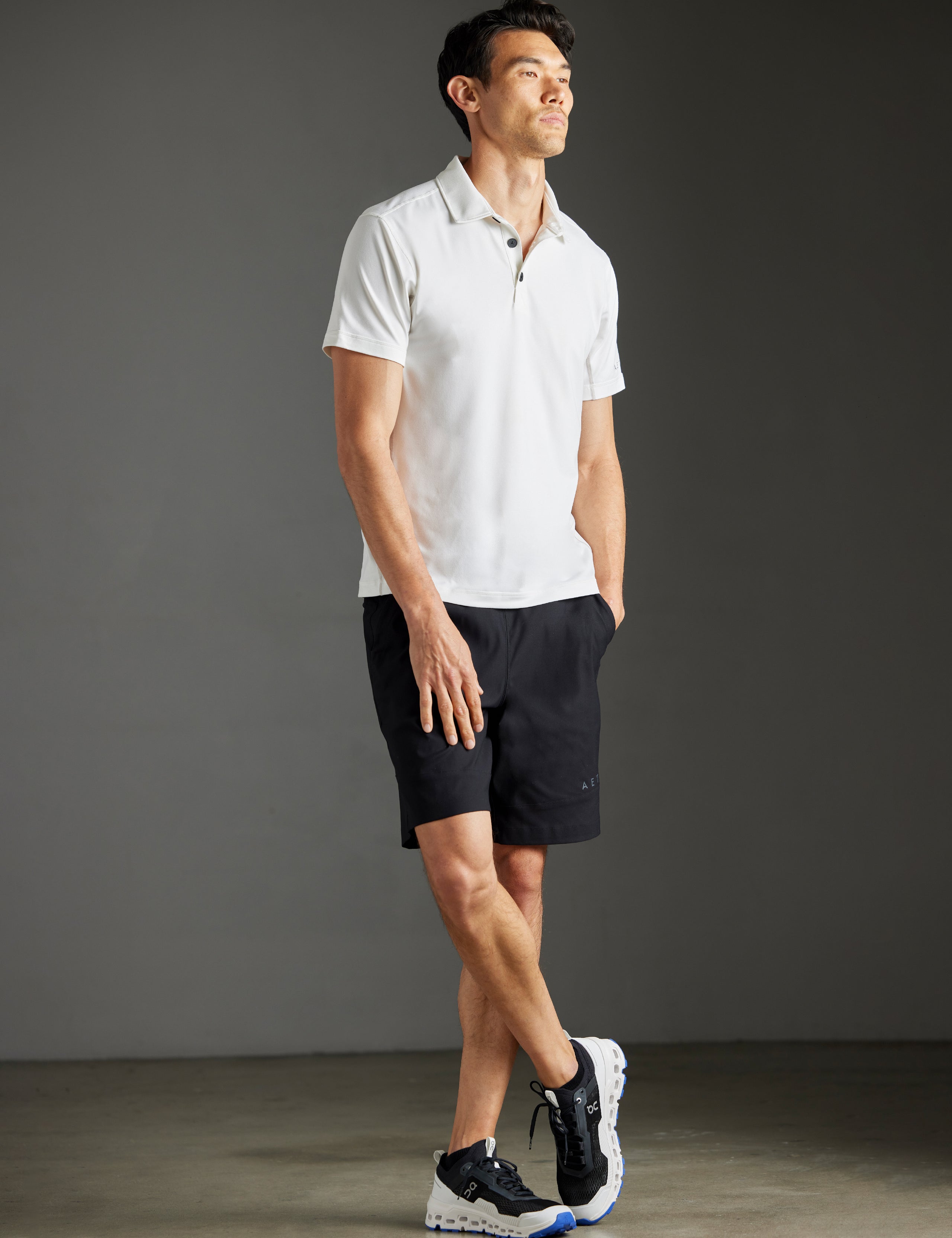 Front 3/4 full-body view of man wearing Trek Articulated Polo in Natural White from AETHER Apparel.