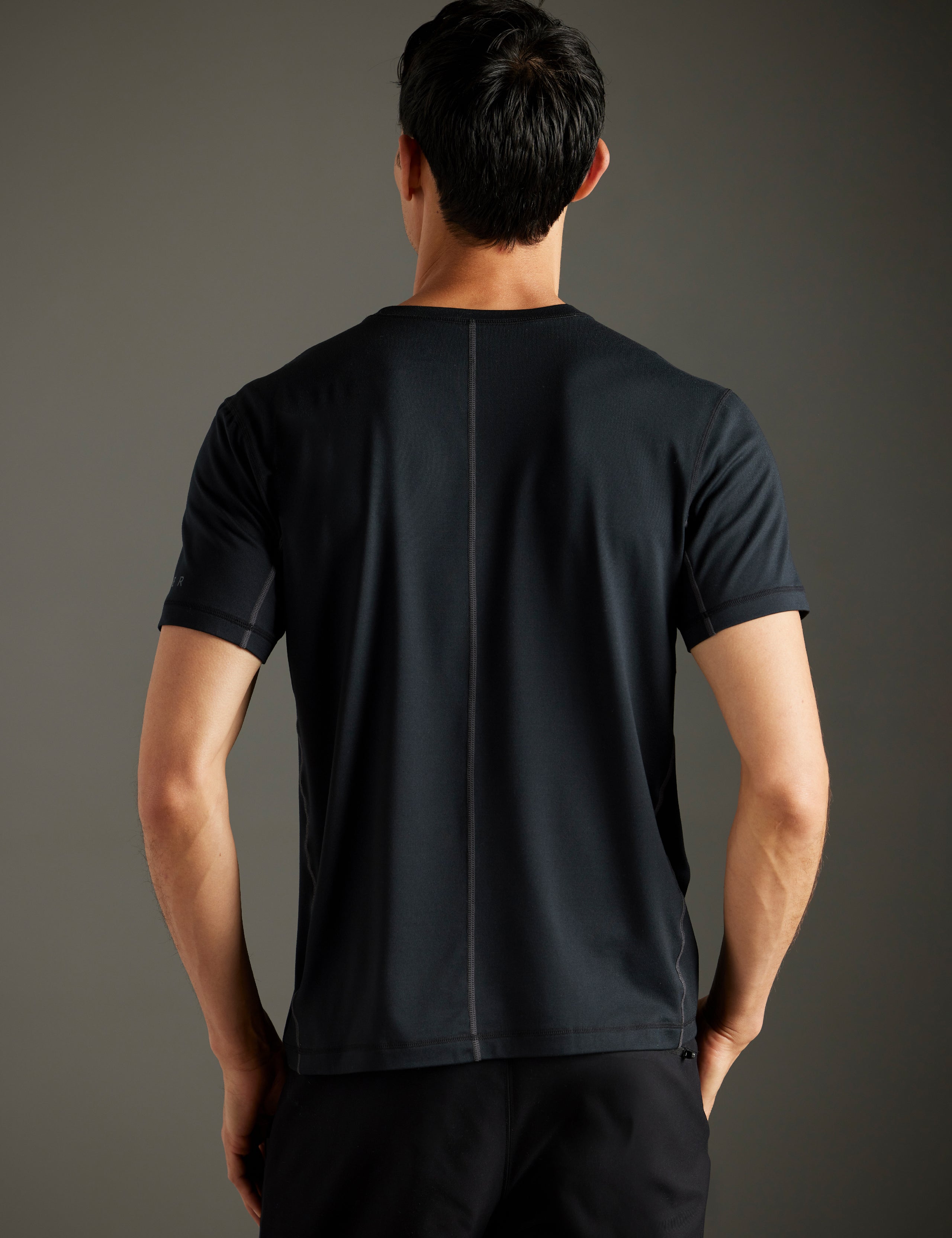 Rear body view of man wearing Trek Articulated Tee in Onyx Black from AETHER Apparel.