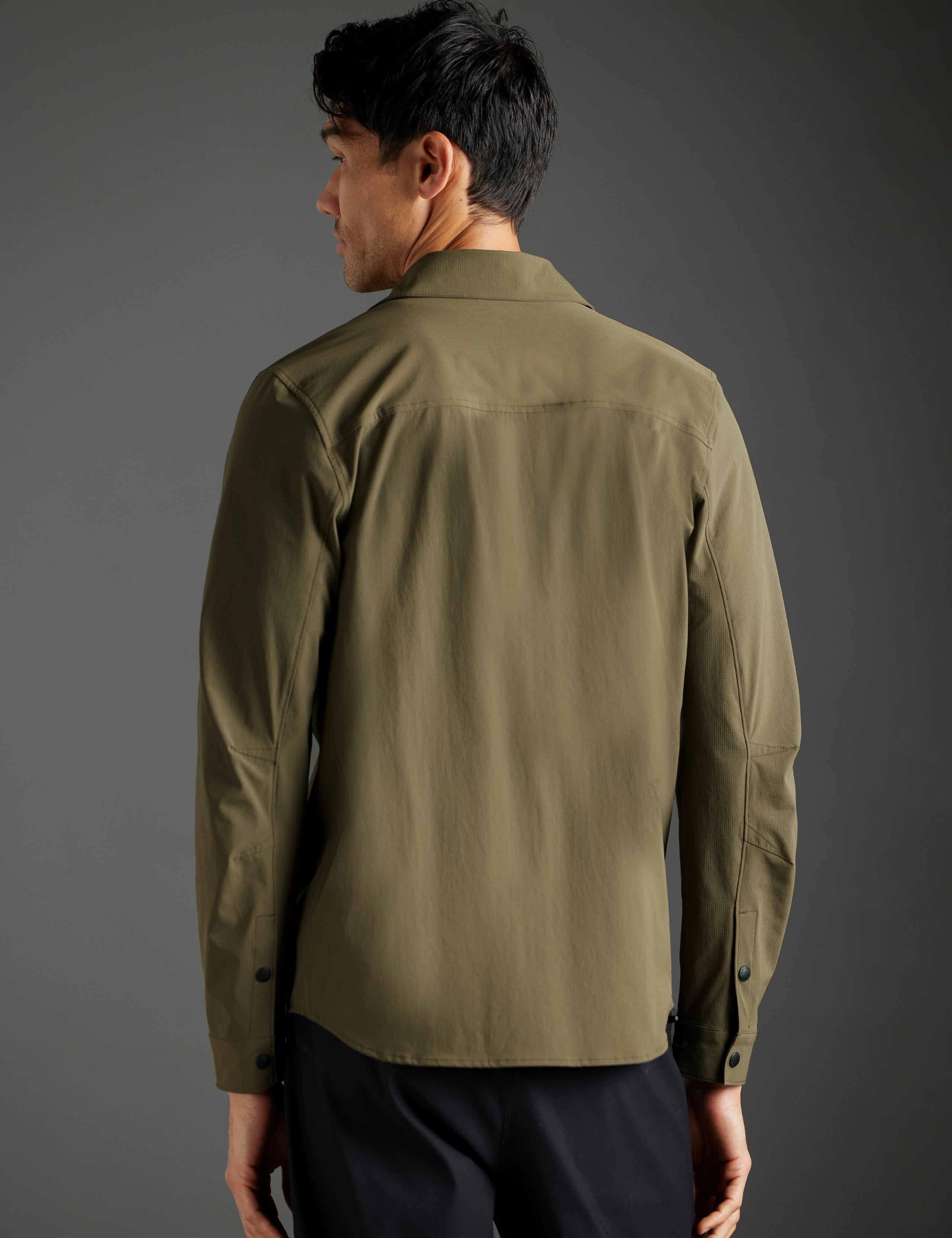 Rear body view of man wearing Wonder Technical Button-Down in Cadet green from AETHER Apparel.
