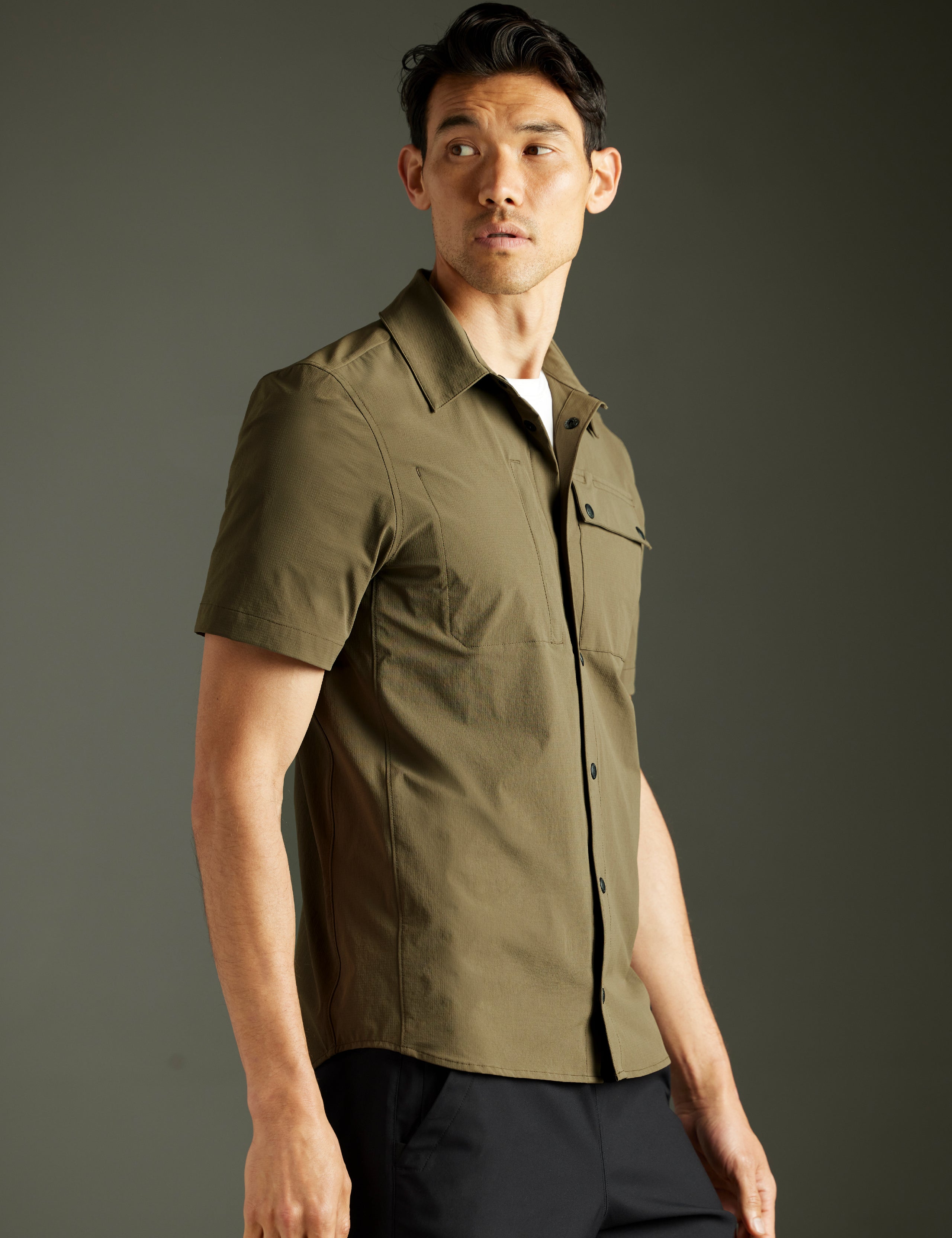 Front 3/4 body view of man wearing Wonder Technical Short-Sleeve Button-Down in Cadet green from AETHER Apparel.