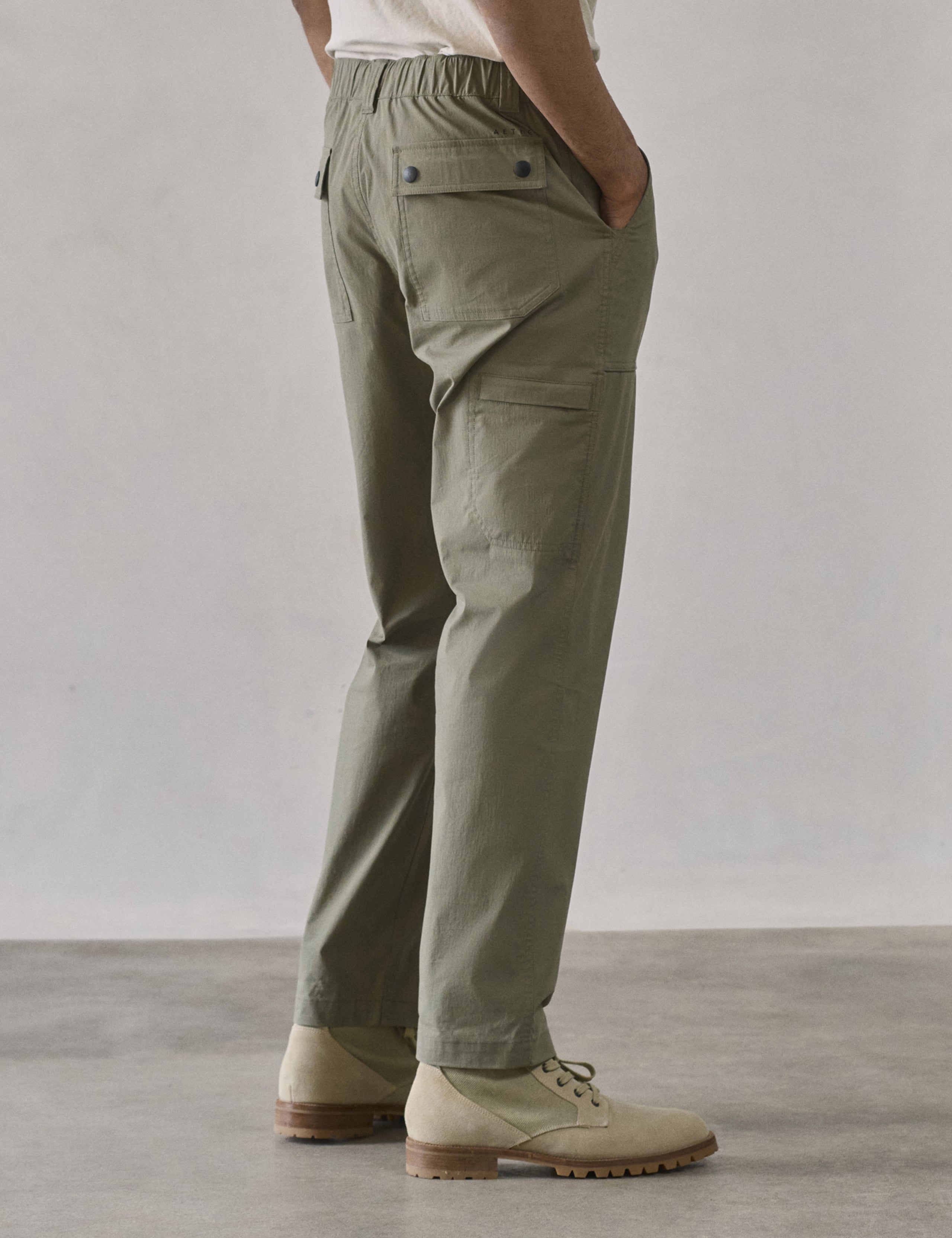 Rear 3/4 lower body view of man wearing Zermatt Hiking Pant in Fern Green from AETHER Apparel.