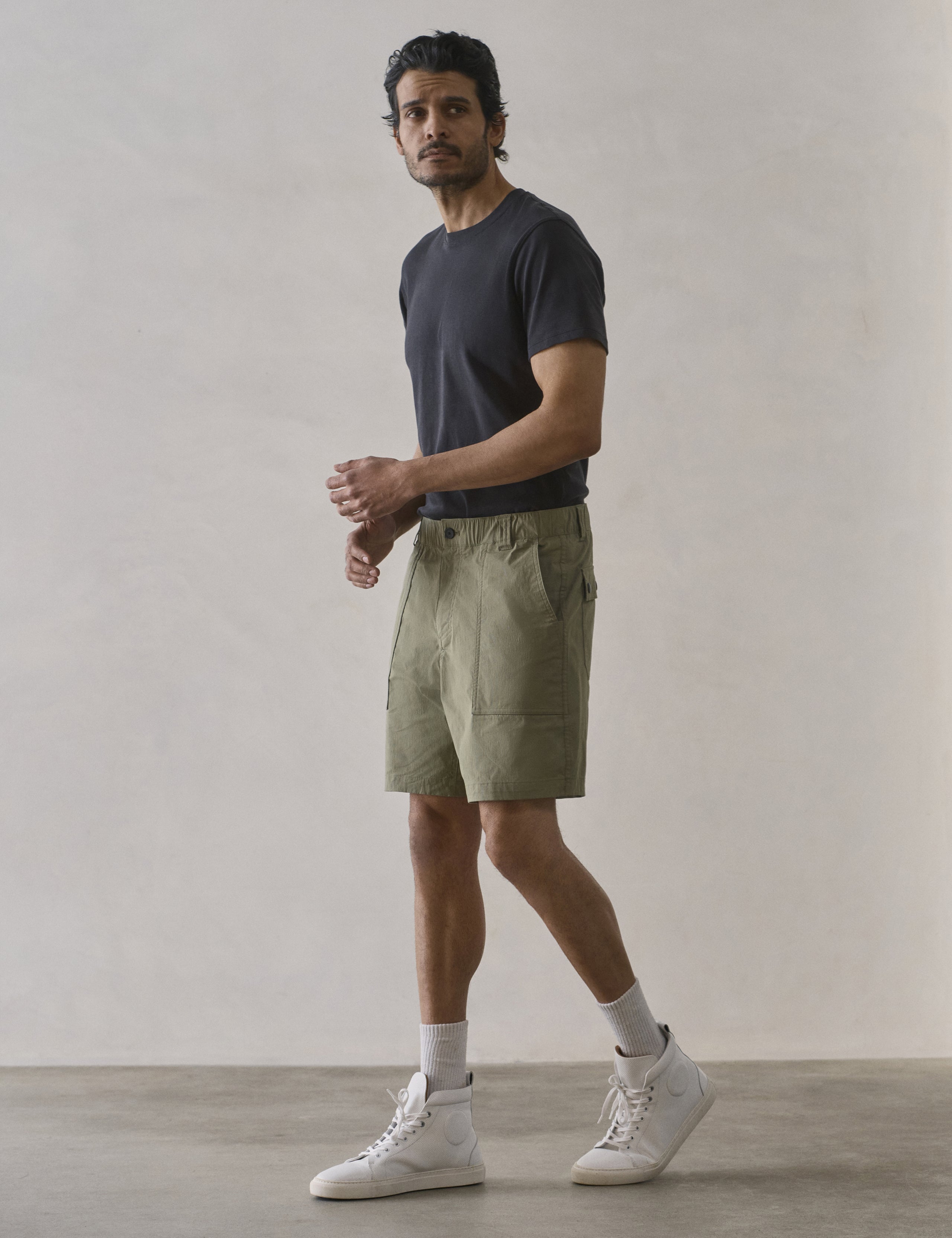 Front 3/4 full-body view of man wearing Zermatt Hiking Short in Fern Green from AETHER Apparel.