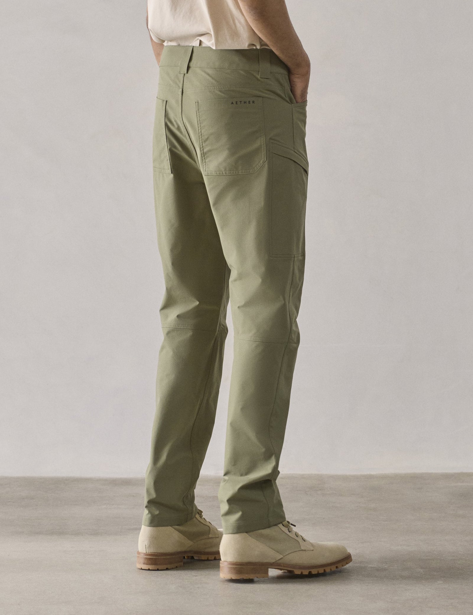Rear 3/4 lower-body view of man wearing Adventure Pant in Fern Green from AETHER Apparel.