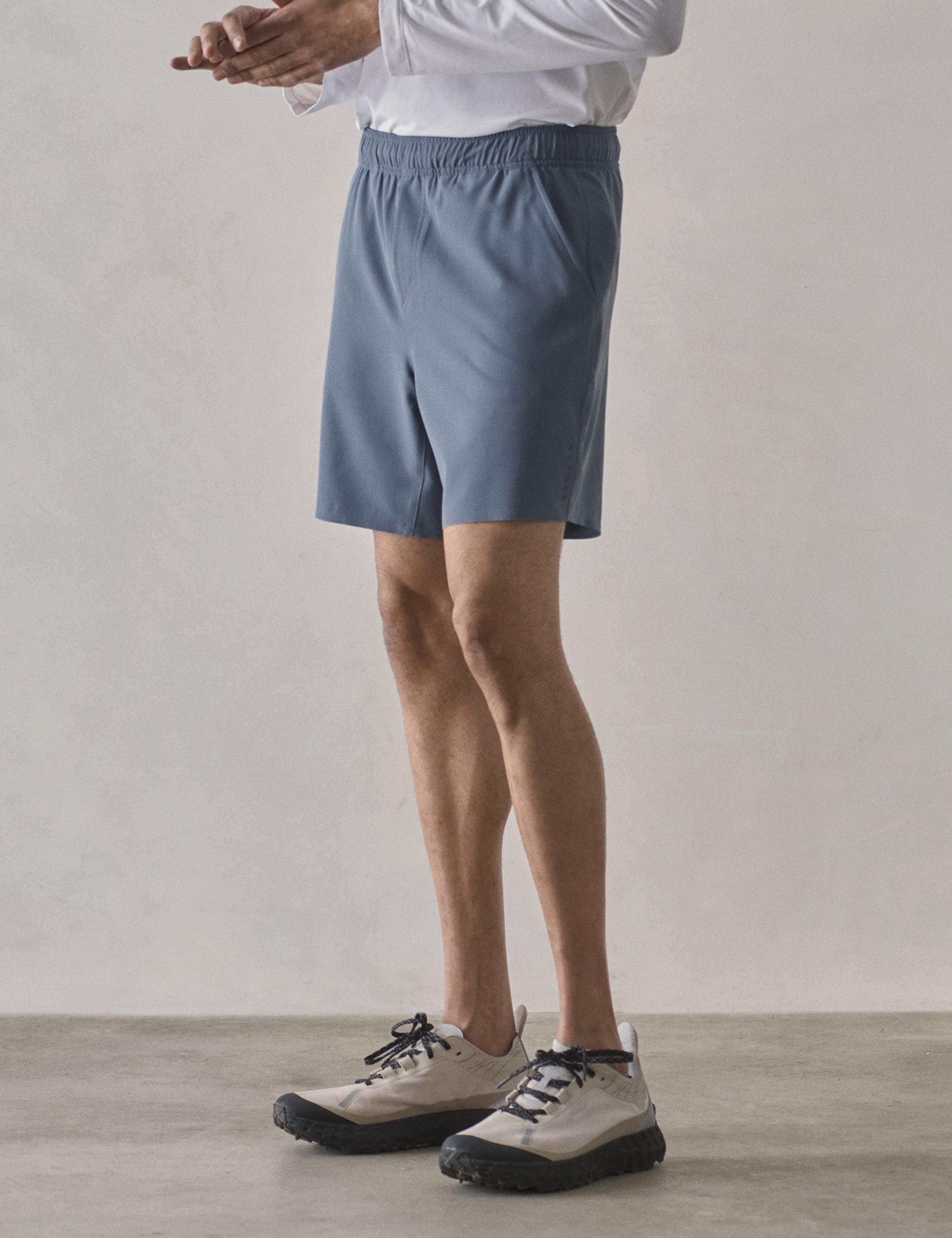 Front 3/4 lower-body view of man wearing Rogue Hybrid Short in Portal Blue from AETHER Apparel.