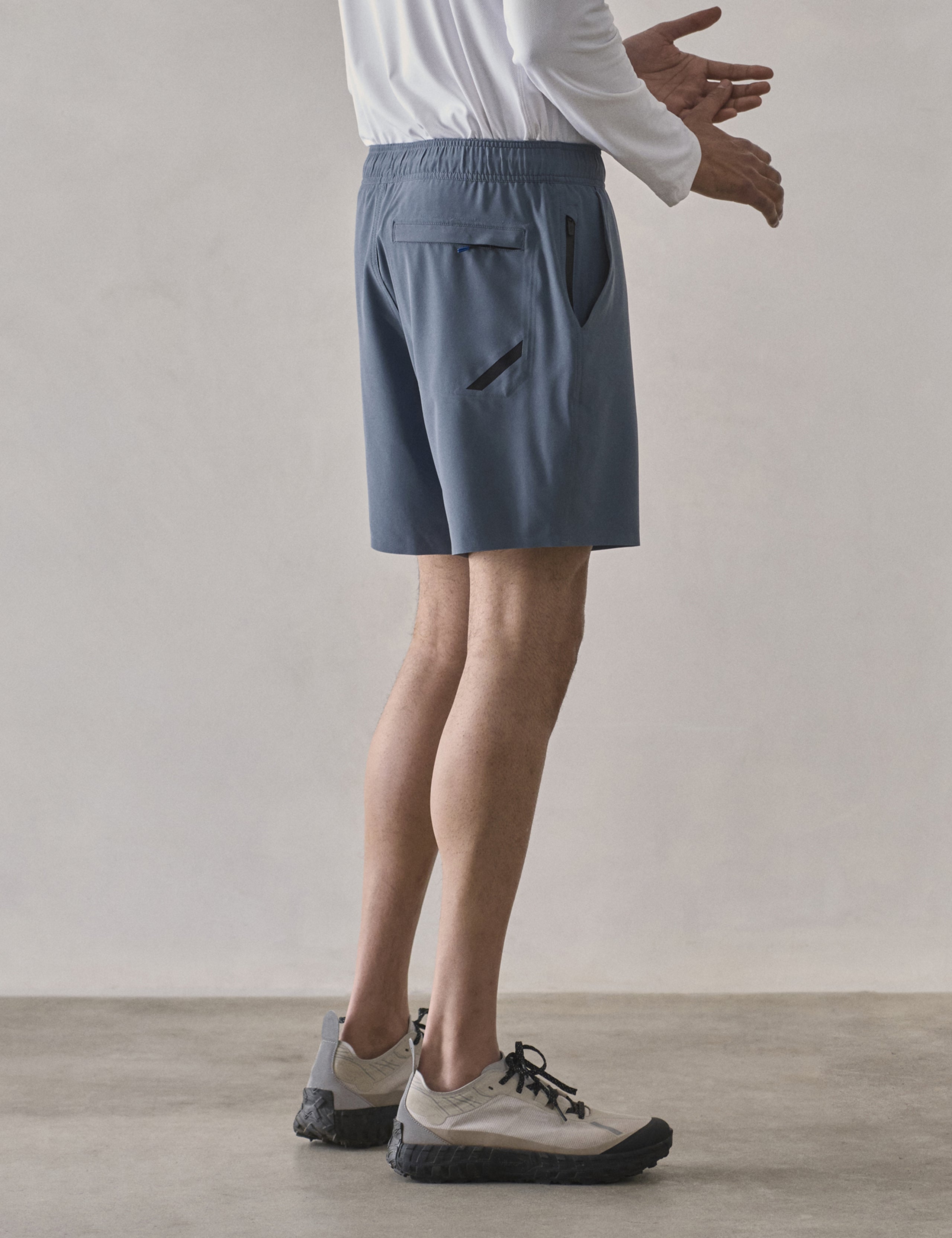 Side profile lower-body view of man wearing Rogue Hybrid Short in Portal Blue from AETHER Apparel.