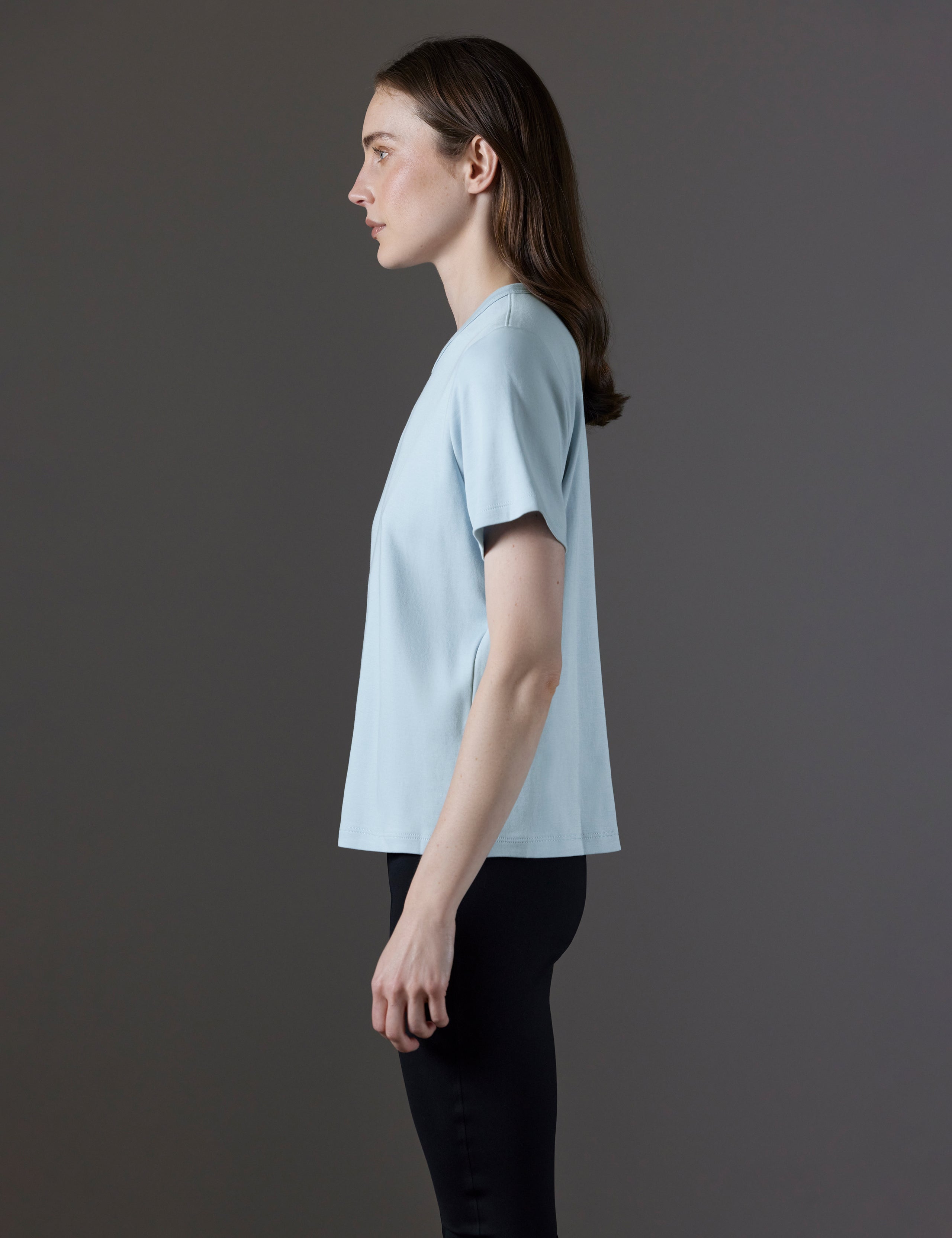 Side profile view of woman wearing Emery Pima Tee in Flight Blue from AETHER Apparel.