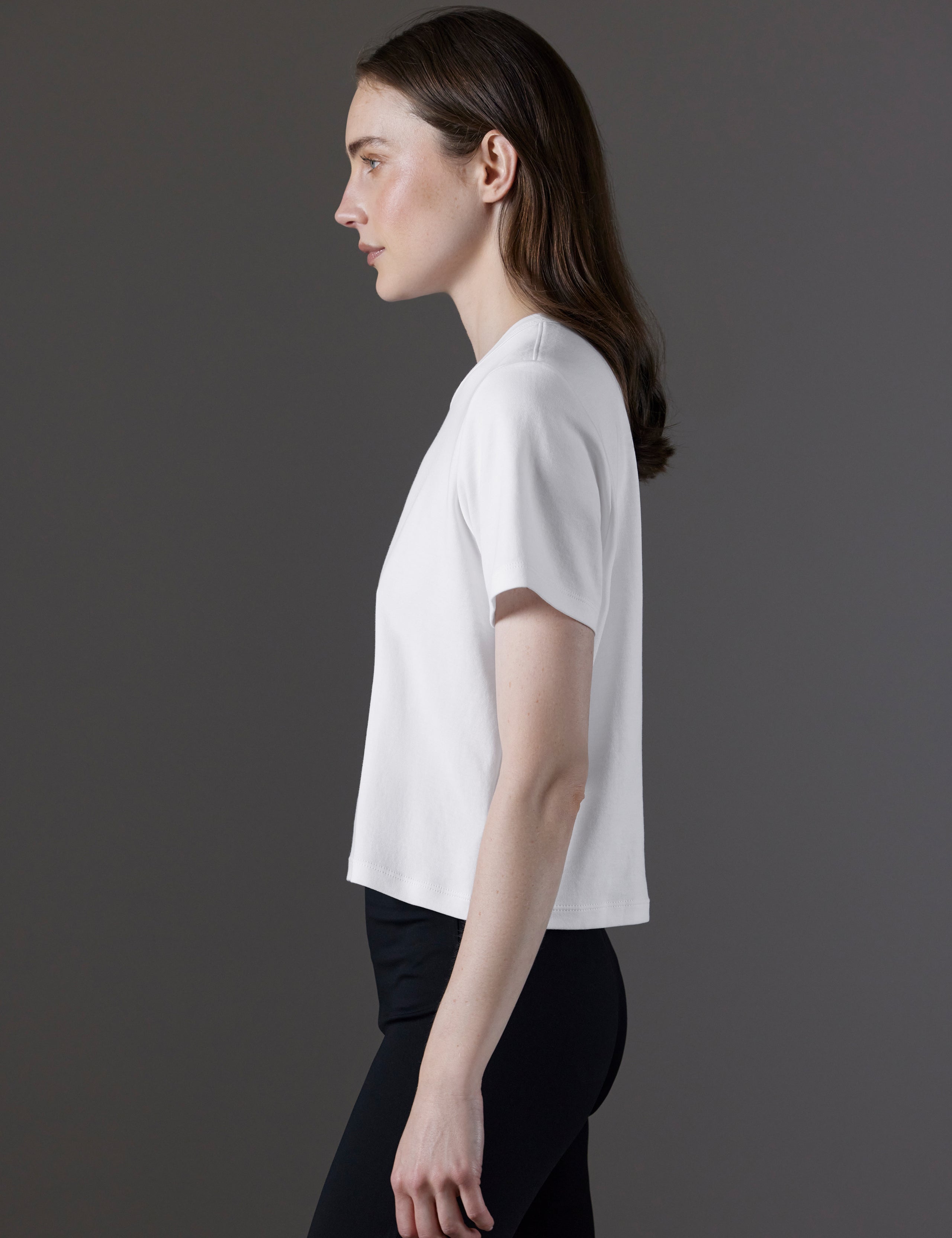 Side profile view of woman wearing Emery Pima Cropped Tee in White from AETHER Apparel.