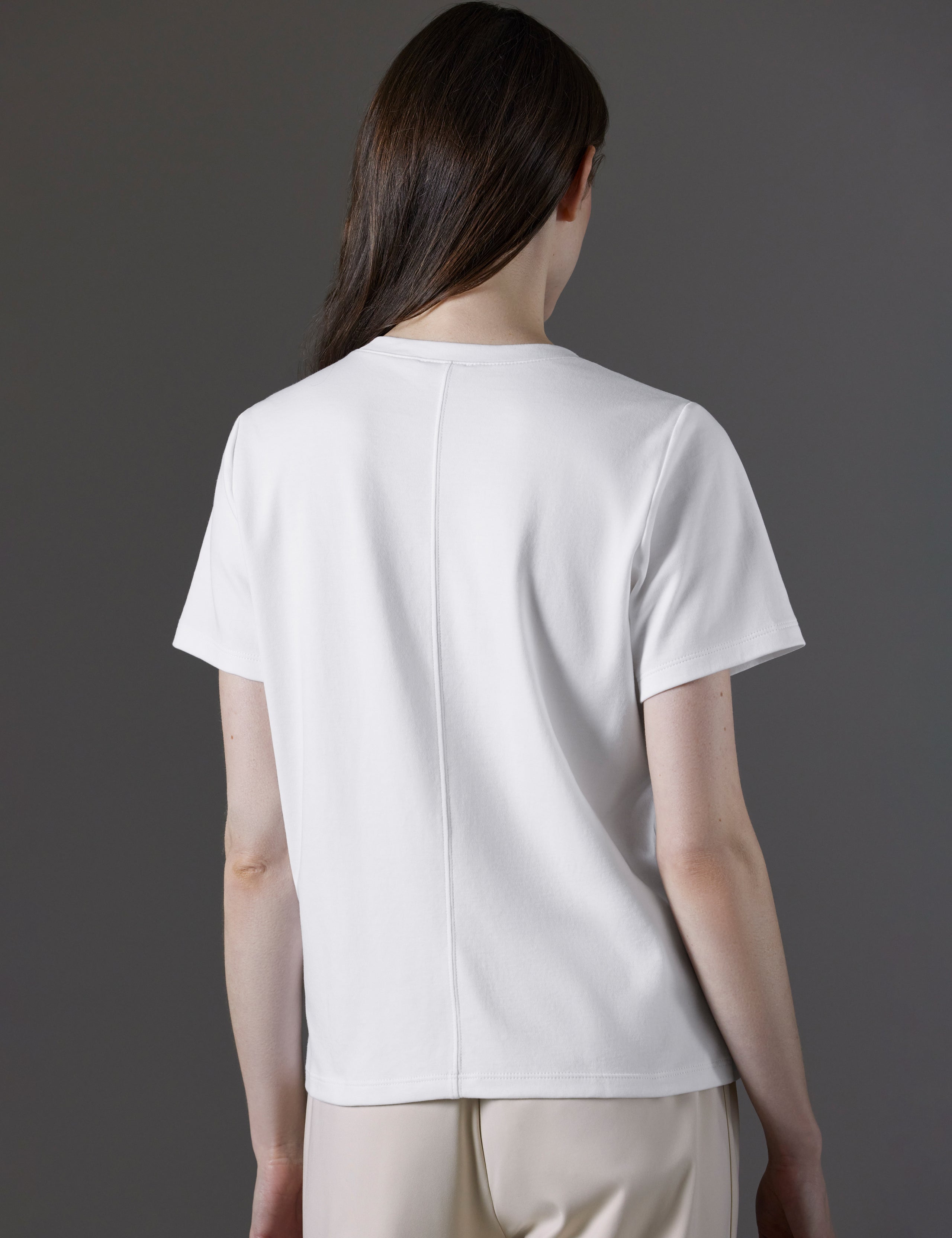 Rear angled view of woman wearing Emery Pima V-Neck Tee in White from AETHER Apparel.