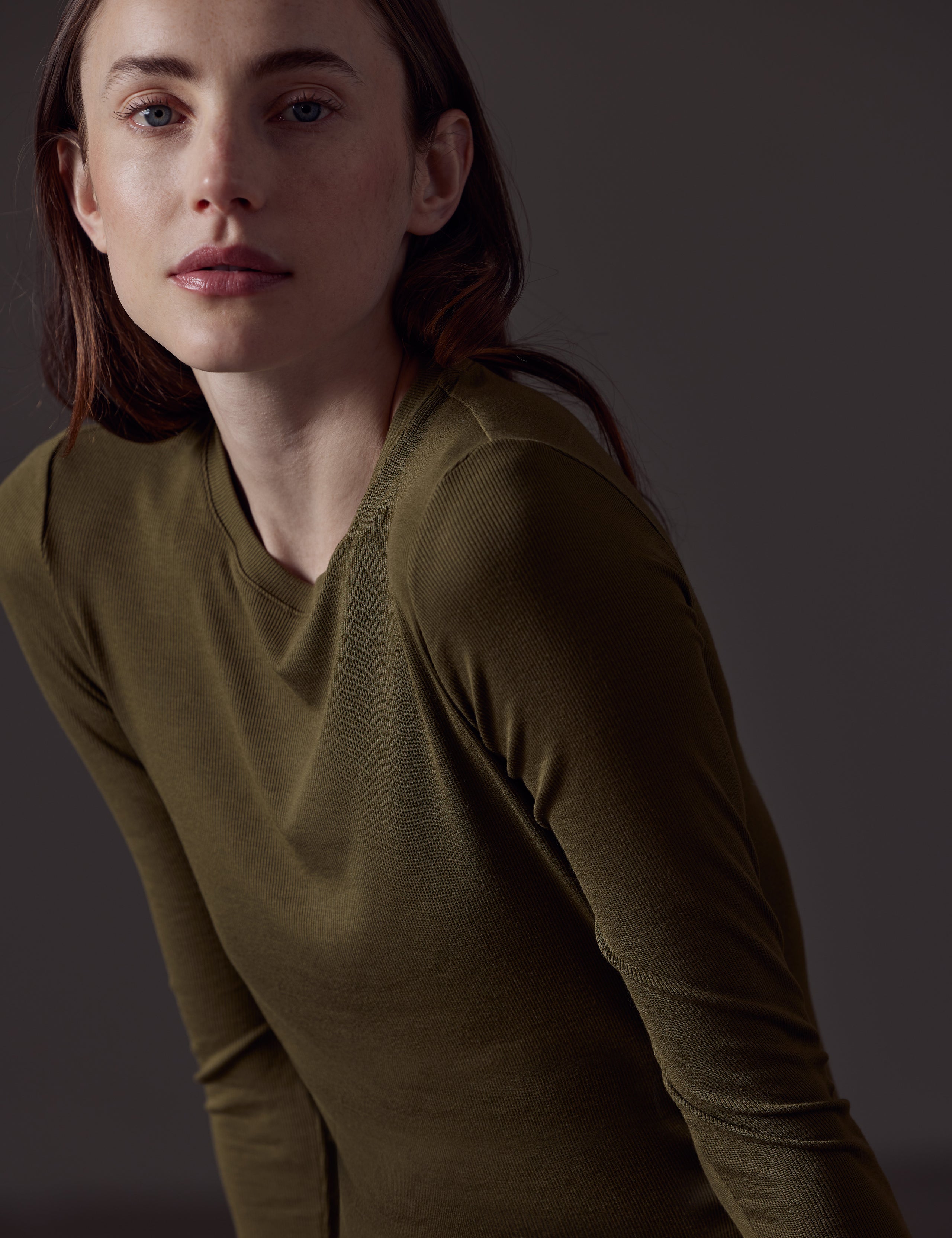 Closeup front angled view of woman wearing Legacy Long-Sleeve Crew in Command Green from AETHER Apparel.